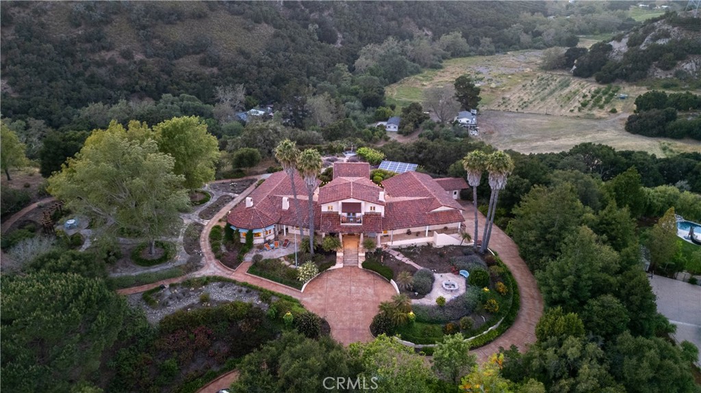 Behind the gates of Bassi Ranch, discover an exceptional Spanish/French Country estate nestled on 2.65 acres of beautifully landscaped grounds. This
custom home offers an elegant blend of timeless design and modern comfort, framed by meandering pathways, peaceful courtyards, tranquil mountains, pergolas, and sweeping views of rolling hills, with a glimpse of the ocean. The main residence of 5523 sq. ft. includes three bedrooms and four baths, while an additional 384 sq ft detached casita, with its own bath provides flexible space for guests or multigenerational living. A 4-bay garage with ample storage and an additional detached garage for garden and tractor equipment adds unmatched utility. From the moment you enter through the stately front gate and drive down the long, landscaped driveway, you’ll be captivated by the home’s extraordinary craftsmanship. Curved walls, intricate ceilings, arched windows and doors, built-in cabinetry, and handcrafted tiles showcase the authentic detail rarely seen today. Fresh
interior paint and updated kitchen accents enhance the warm and inviting atmosphere. The open floor plan centers around a grand living room and
formal dining area, ideal for entertaining. The gourmet kitchen features premium appliances, a center island with bar seating, and a breakfast nook
with direct access to a lush botanical garden, seamlessly blending indoor and outdoor living. Dual primary suites offer flexible luxury: the main-level suite includes a private office or den and a spa-style bathroom with a soaking tub and walk-in shower. The upper-level suite features a private deck with panoramic views, and both include spacious walk-in closets. Additional spaces include a versatile library/game room serving as a home theater,
man cave, woman's cave, or a second formal dining room, and a separate guest en-suite that opens to a central courtyard. A cozy billiard room with
custom-built-ins offers a relaxing retreat. With four bedrooms, two libraries, four garage bays, and a separate utility garage, every bedroom suite is very independent. This estate offers serenity, privacy, and space—just minutes from beaches, renowned wineries, and downtown San Luis Obispo. Don’t miss this rare opportunity to own a truly remarkable piece of California living.