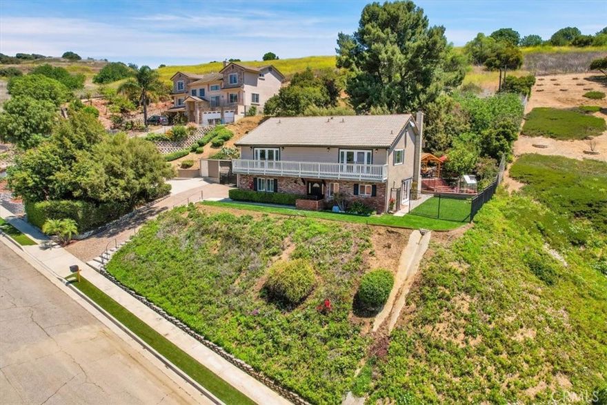 Views! Views! Views!  Located in the scenic hillside community of Olinda Village, this stunning 4 bedroom, 2.5 bathroom home boasts panoramic views of Carbon Canyon and tranquil surroundings; on a clear day giving way to see Catalina Island.  The first floor features an open-concept layout that seamlessly connects the kitchen, dining area, and living room. The kitchen is a standout with its bright white cabinetry, tan and black granite countertops, built-in double ovens, range cooktop, dishwasher, center island, and pantry for ample storage. The adjoining living room includes a cozy fireplace and access to the backyard, creating a warm and welcoming space to gather. A laundry room on the main floor adds convenience with built-in cabinetry, a utility sink, and countertop space for folding. The powder room also features direct access to the backyard — ideal for guests during outdoor gatherings. Upstairs, you’ll find a versatile loft complete with a wet bar, built-in wine fridge, and balcony access to amazing views; the loft offers endless potential as a game room, office, or lounge. All four bedrooms are located on the second floor for added privacy, along with a stylish hall bathroom featuring an oversized wood vanity, granite countertops, glass shower doors, and gray tile flooring. The primary suite is spacious and serene, with balcony access to vast views in the peaceful hilltop, a walk-in closet featuring custom built-in cabinetry, and a beautifully appointed ensuite bathroom. The primary bath boasts dual vanities, a dedicated makeup vanity, a walk-in frameless glass shower with subway tile and mosaic rock accents, and ample storage cabinetry. The backyard is a true extension of the home, offering a blend of grassy areas, concrete and brick hardscaping, and a large, shaded gazebo to enjoy the most stunning views in the neighborhood. The generous lot offers the potential to build an ADU.  This home is equipped with smart home features, including a Lutron lighting control system that allows you to manage lighting right from your phone. A 12-kilowatt solar system with a 10-kilowatt backup battery is fully paid to help reduce energy costs. The 16-zone Ring sprinkler system ensures your landscaping stays lush with minimal effort.  This home is a rare combination of natural beauty, modern functionality, and flexible living space, all in a peaceful and sought-after hillside community while only minutes away from Downtown Brea!  **Check out the virtual tour!**