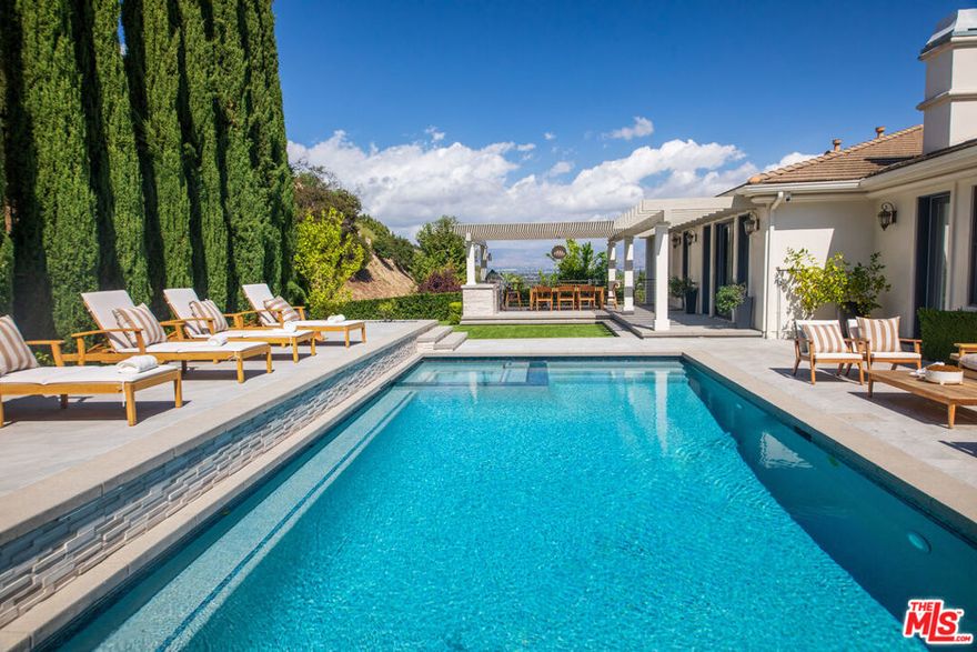 Furnished & Turn-Key, this exquisite residence is set within the exclusive enclave of The Benedict Collection at the southern edge of Sherman Oaks. One of only seven homes tucked at the end of a peaceful cul-de-sac, the property captures sweeping views of the San Fernando Valley and the San Gabriel Mountains. Completely reimagined with meticulous attention to detail, it blends timeless elegance with the ease of modern indoor-outdoor living. The formal living room opens to a manicured backyard featuring a large pool and spa, lush lawn, and expansive lounge deck  perfect for both refined entertaining and casual relaxation. The chef's kitchen is a true showpiece with custom cabinetry, premium appliances, a large center island, and a bright breakfast nook overlooking the valley. A poolside dining pergola with a full outdoor kitchen completes the entertainer's dream setting. The primary suite offers a serene retreat with a fireplace, private office or sitting room, and a spa-inspired marble bath. Additional highlights include a family/media room, and guest suite on the main level, and a lower level with a mirrored gym, private theater, playroom or den, laundry, and three en-suite bedrooms. Elegant, private, and effortlessly livable  this turn-key estate embodies elevated California living at its finest.