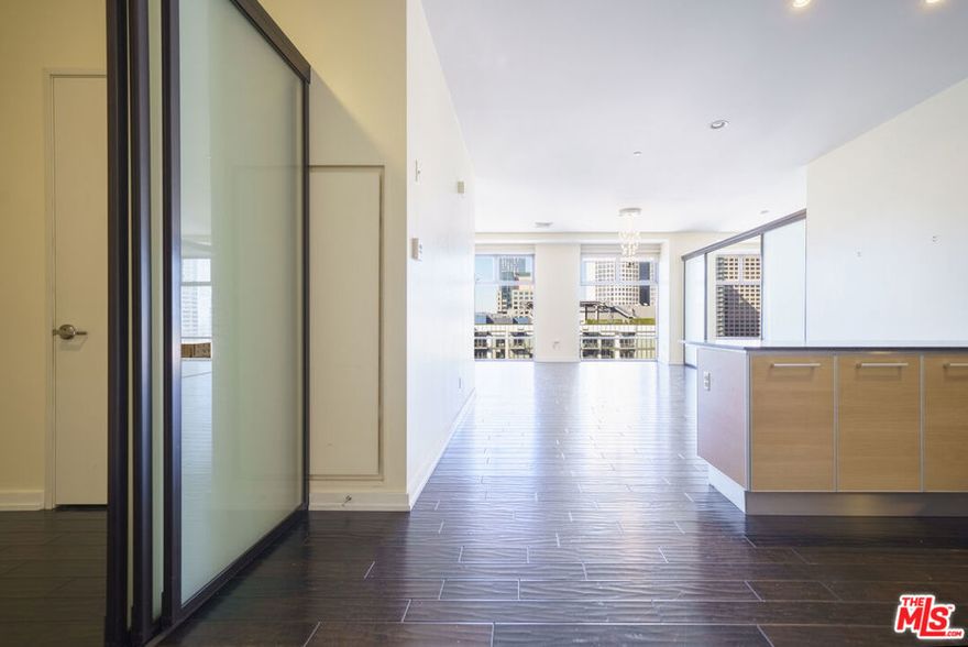 Perched on the 19th floor of Sky Lofts, this spacious two-bedroom, two-bath residence offers a versatile floor plan and sweeping west-facing city views. Natural sunlight fills the home by day, while soothing nighttime views create the perfect urban retreat. The primary bedroom features a generous walk-in closet and a sleek sliding glass enclosure, maintaining an open, loft-style aesthetic while offering privacy. A flexible den/office area also includes a sliding enclosure ideal for working from home or additional living space. The spacious kitchen is well-appointed with a breakfast bar that flows effortlessly into the main living area, perfect for entertaining or everyday living. Sky Lofts is a full-service building offering 24/7 front desk and security, along with a part-time on-site manager. Residents also enjoy access to a spacious business center and recreation room with kitchen, a private tv/movie screening room, and a fully equipped fitness center. Additional highlights include two side-by-side, assigned parking spaces conveniently attached to the building. Located in one of Downtown LA's most walkable neighborhoods, Sky Lofts places you just steps from Whole Foods, The Bloc, FIGat7th, Ralphs, and a vibrant mix of restaurants and coffee shops including Bottega Louie, Philz Coffee, Joyce, Alamo Drafthouse, Hatch, and more. Enjoy nearby FIDM Park, easy access to the Metro, and seamless connectivity to the Historic Core, Social District, and Financial District - Elevated city living in the heart of Downtown Los Angeles.