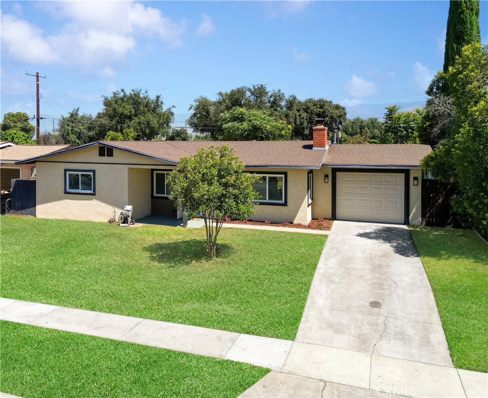 WELCOME HOME to this true gem in the heart of Redlands! Centrally located on a large lot with a long driveway and charming curb appeal, this home offers a perfect blend of comfort and convenience. Step inside to find a beautifully updated interior featuring tile flooring, a neutral color palette, and recessed lighting that enhances the abundant natural light. The remodeled kitchen is a chef's delight, boasting upgraded white cabinetry, stainless steel appliances, a farmhouse sink, and a breakfast bar that opens seamlessly to the dining and living areas—perfect for entertaining. The dining room features a ceiling fan and sliding glass doors that lead to the spacious covered patio, while the inviting living room includes a cozy brick fireplace and new windows. You’ll find three generously sized bedrooms with plush carpeting, including a primary suite with a private updated bath, a large vanity, and a walk-in shower. The equally stylish hall bath features decorative tile and mosaic accents. The expansive backyard is a blank canvas with lush grass and a large covered patio—ideal for gatherings, barbecues, or relaxing. With a huge lot, there's endless potential for an ADU or home additions. Additional features include a one-car garage with a laundry area, beautiful mountain views, newly laid mulch and flowers, and central HVAC throughout. Don't miss the chance to own this beautifully updated Redlands home!