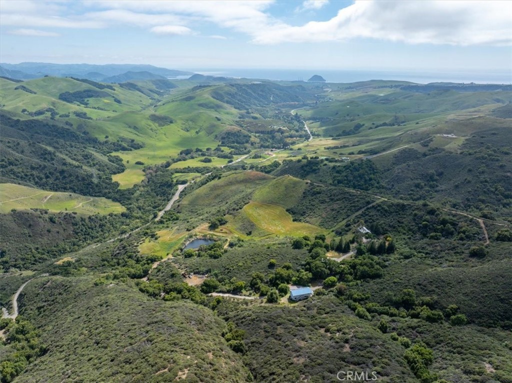 Legacy Coastal Ranch with Panoramic Ocean & Hillside Views – 85± Acres
A rare opportunity to own a truly remarkable piece of the California coast. This legacy 85± acre ranch features two separate living structures—the main residence and a spacious shop apartment—offering versatility, privacy, and a range of living or rental possibilities. With sweeping ocean and hillside views, unmatched privacy, and a connection to nature that’s increasingly hard to find—just 7± miles from the Pacific Ocean—it’s the ultimate place to unplug from the world and reconnect with what matters most.
The main residence was thoughtfully rebuilt in 2003 with meticulous attention to detail. Every inch of this custom-built 1 bed / 1.5 bath home reflects the owner’s lifelong dream of creating the perfect nature-focused getaway. Step outside the kitchen onto a large deck that overlooks an idyllic pond and rolling hills—perfect for morning coffee, sunset views, or simply soaking in the peaceful surroundings.
A second two-story, 3,000± sq ft residence offers endless possibilities. Currently tenant/caretaker-occupied, the open-concept 2 bed / 2 bath home could easily be converted into two separate units. Below, a spacious three-bay garage/shop includes a half bath and ample storage. With selective tree thinning, breathtaking views of Morro Rock can be revealed. Also included is a 1,200± sq ft detached shop—ideal for hobbyists, creatives, or equipment storage.
Scattered across the ranch are multiple scenic building sites with stunning ocean vistas. Surrounded by protected BLM land, the property guarantees enduring privacy and unspoiled natural beauty. Wildlife and native plants flourish across the landscape, and several cleared acres are ready for a future orchard or garden. Two strong springs supply fresh water to a 14,000± gallon tank that serves both homes. The overflow keeps the picturesque pond full year-round, supporting fish and enhancing the property’s tranquil atmosphere. A gated, paved access road provides both privacy and convenience.
This is more than just a home—it’s a true coastal sanctuary where you can slow down, breathe deep, and embrace a lifestyle rooted in nature. Don’t miss this once-in-a-lifetime opportunity. Call today to schedule your private showing.