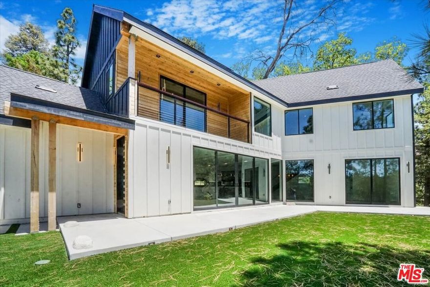 Discover this newly built, stylish two-story contemporary home in the esteemed North Bay area, offering a fresh and inventive approach to mountain living. Positioned on a level corner lot at the end of a cul-de-sac, the home enjoys seclusion under a canopy of immaculate trees. Expansive sliding doors define the entire open-concept design, creating the street-level facade. Features include high beamed ceilings, custom 8-foot doors, a sleek 8-foot wide horizontal fireplace, and a floating staircase, along with a spacious street-level bedroom and full spa bathroom. A natural stone-embedded concrete patio stretches the length of the home's exterior, featuring a Zen garden and a pad for a jacuzzi at the end.Upstairs, four additional bedrooms and two baths offer breathtaking mountain and forest views, complemented by expansive decks. The unique primary bedroom boasts an open floor plan with a custom "loft" style wall separating the bedroom area from a vast walk-in/open closet. The exterior walls, constructed from reclaimed wood, are paired with state-of-the-art products and building materials, including solar panels and automated temperature control. Additional features include an electronic front door and an electric car charger. This energy-efficient smart home stands out as a rare gem in the Mountain Resort Communities of Lake Arrowhead.