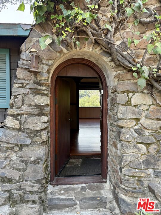 Escape to a soulful 1920s hideaway in the heart of Topanga Canyon. Tucked away on a quiet road, this rustic one-bedroom home is filled with character-vaulted ceilings, wood floors, a dramatic stone fireplace with wood-burning stove, and a dining room wrapped in windows and light. There's a spacious bathroom, kitchen, and a large inside laundry room with washer and dryer as well. A detached studio with Wi-Fi and endless windows makes the perfect creative workspace. Outside, a wide grassy lawn, mature trees and private nooks offer room to dream, garden, catch a sunset or gather under the stars. Rumored to once be Teddy Roosevelt's hunting lodge, this home is more than a lease- it's an inspiring sanctuary for artists, writers, and free spirits.