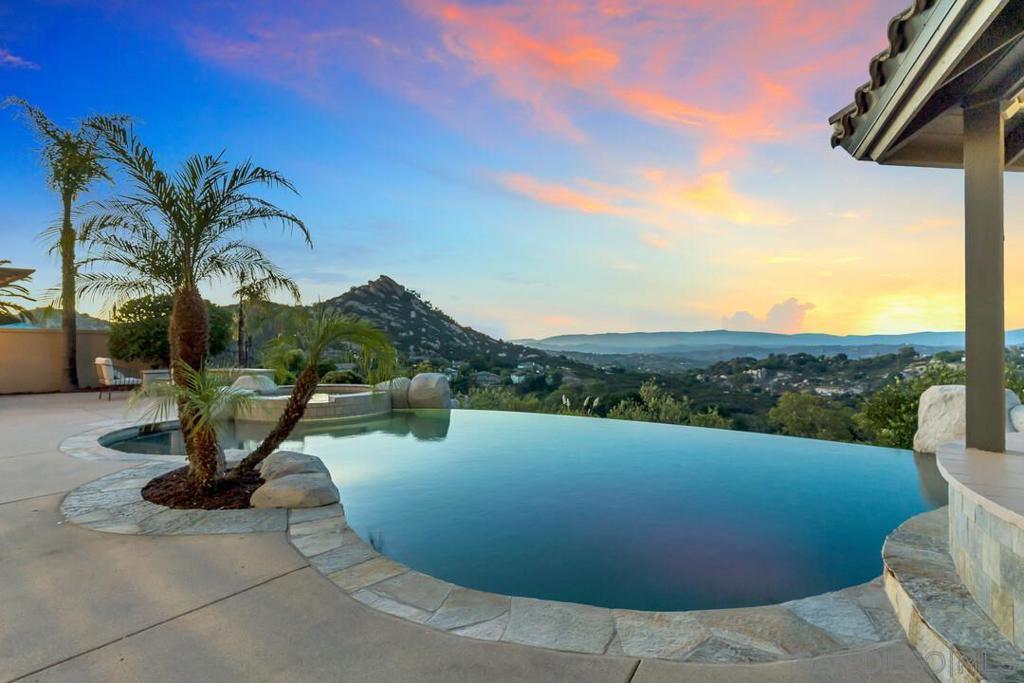 Enjoy majestic Mt Woodson & Ramona Valley views from this award-winning Mt Woodson golf course gated community. Beautiful 4-bedroom plus optional bedroom, this home is perched on a private and serene elevated lot. This exceptional property showcases sweeping panoramic views and a resort-inspired backyard designed for ultimate outdoor living. Enjoy a solar-heated Pebble Tech vanishing edge pool, Baja shelf and spa with a brand-new interior and waterfall, granite BBQ island with seating for eight, built-in fridge, tile-roofed gazebo with fireplace, and a separate fire pit, perfect for relaxing or entertaining. Inside, the open-concept great room features vaulted ceilings, oversized windows, and an abundance of natural light. A peaceful entry courtyard with a water feature sets the tone for the home’s tranquil ambiance. Recent upgrades include a new tile roof (2020), two Lennox HVAC systems (2020 & 2024), newer water heater, freshly painted exterior and trim (2025), new interior paint and carpet, and updated outlets and switches. Additional highlights include a 3-car garage, 5-foot privacy walls, and a floor plan that blends comfort and elegance. Meticulously maintained, this is one of Mt. Woodson’s most impressive homes, offering privacy, luxury, and unforgettable views.
