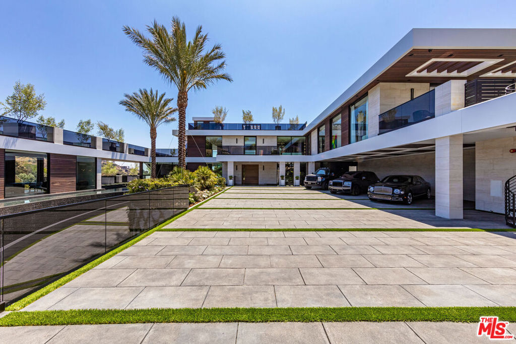 A spectacular contemporary estate built in 2021 located behind gates on over 1.2 acres of land. Situated above dazzling city lights, this sprawling state-of-the-art home has sweeping views (including unobstructed Getty, city & ocean views). Incredible scale, walls of glass, indoor/outdoor areas for entertaining, water features and true resort style living. The gated compound sits on a private cul-de-sac in exclusive Brentwood, N. of Sunset. Automobile showroom separated by floor-to-ceiling glass walls that open to an expansive lounge anchored by a 9-TV media wall, bar & barbershop. State-of-the-art gym w/sports simulator room, indoor pool & spa. Exterior lower-level w/Kobe Bryant inspired NBA-sized basketball half court, outdoor seating & gym overlooking the city. Amenities include modern office, open-concept kitchen, 1000-gallon dual sided aquarium, prep kitchen, double height living room, 2-story guest house, balconies, city view putting green, 30' living wall, world class primary suite w/spa bath & boutique worthy closets, & so much more. Outdoor oasis thru automatic glass pocket doors w/verdant lawn, cabana w/custom TV, bar, pizza oven, infinity edge pool w/Baja seating & spa, inviting sun-soaked relaxation year-round.