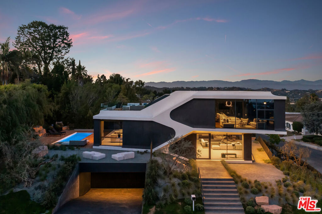 A true architectural masterpiece, this award-winning Bel Air Estate-recipient of many prestigious design honors defines modern luxury. Completed in 2022, this 4-bedroom, 5-bath residence blends automotive-inspired design with cutting-edge CNC-milled precision. A bold 16-foot cantilevered second floor creates a dramatic canopy over the entrance, setting the tone for the home's visionary style. Inside, the split-level layout is anchored by a frameless glass elevator and open sleek staircase, bathing the interiors in natural light through floor-to-ceiling Belgian glass. Seamless indoor-outdoor living via automated door systems, opening to multiple decks and a lush backyard with pool and spa ideal for relaxing or entertaining! The main level features a voluminous living room with fireplace, soaring ceilings, and a sleek family lounge. Just above is the dining area and chef's kitchen outfitted with DOCA cabinetry, Dekton surfaces, and walnut detailing flow effortlessly to the outdoor oasis. The primary suite is a sanctuary, complete with glass closets, amber doors, a private lounge, and a spa-grade marble bathroom with Agape fixtures, spacious steam shower and separate tub all framed by panoramic views from the Getty to the Pacific. Spacious rooftop deck just off the primary with pedestal flooring offers unobstructed ocean and city views ideal to unwind and watch the sunset. The museum-quality basement stuns with raw black concrete walls and dynamic home theatre with felt walls, cork flooring, and a custom diffused ceiling light. Three additional en-suite bedrooms feature glass closets, Graff fixtures, Catalano wall-mounted toilets, and imported Spanish tile. Additional features include integrated condenser compartment design for the high efficiency HVAC system, hidden flush doors throughout, minimal linear and pinhole LED lighting design for ambient and task lighting, recessed wall and ceiling housing for smart home keypads and devices, select grade walnut flooring and wall panel designs with Czech crafted hardware, and seamless high quality plaster floors and walls in select rooms and the exterior facade. A modern warm masterpiece, Truly an exceptional find!