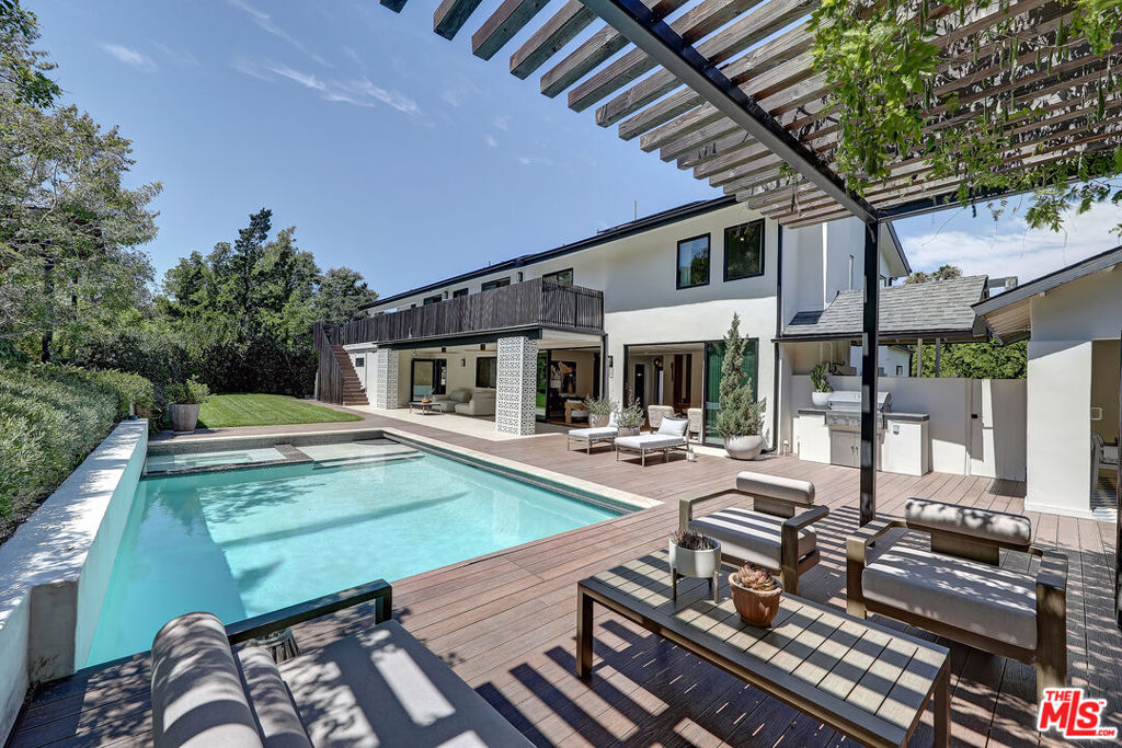 Welcome to a stunning modern retreat in the heart of the Hollywood Hills. This designer-renovated residence, set on a rare half-acre lot, offers unparalleled privacy, a luxurious pool, and expansive panoramic views. Enjoy the convenience of being within walking distance to the Mulholland Tennis Club as well as the prestigious Wonderland School. Spanning nearly 4,000 square feet, this home features five well-appointed bedrooms, blending contemporary elegance with mid-century influences. All the luxury touches are here after spending over $1.2m transforming the home. The chef's kitchen is inspired by Netflix's "Chef's Table" and boasts a grand stove, dual dishwashers, and a generous island. An adjacent dining room offers ample storage and includes multiple wine storing fridges. Eco-conscious elements enhance the home's appeal, with premium solar panels and backup batteries that significantly reduce energy costs. The master suite serves as a luxurious retreat, complete with a private balcony with steps to the pool. An upstairs wrap-around deck provides stunning vistas of the surrounding landscape including amazing views and sunsets. This property is designed for both relaxation and entertainment. The expansive backyard includes multiple seating and dining areas, a lush lawn, and an exceptional outdoor movie and sound experience with a private projector screen, perfect for hosting unforgettable gatherings. Situated at the end of a peaceful cul-de-sac in the sought-after Laurel Hills neighborhood, the home is surrounded by wide streets, sidewalks, and underground utilities. The nearby Mulholland Tennis Club offers not only tennis facilities but also a vibrant social scene. This remarkable home is a rare find, epitomizing luxury and comfort. It's an opportunity to own a dream residence that seamlessly marries modern design with functional living. Don't miss out on this extraordinary property, trust your instincts and make it yours.