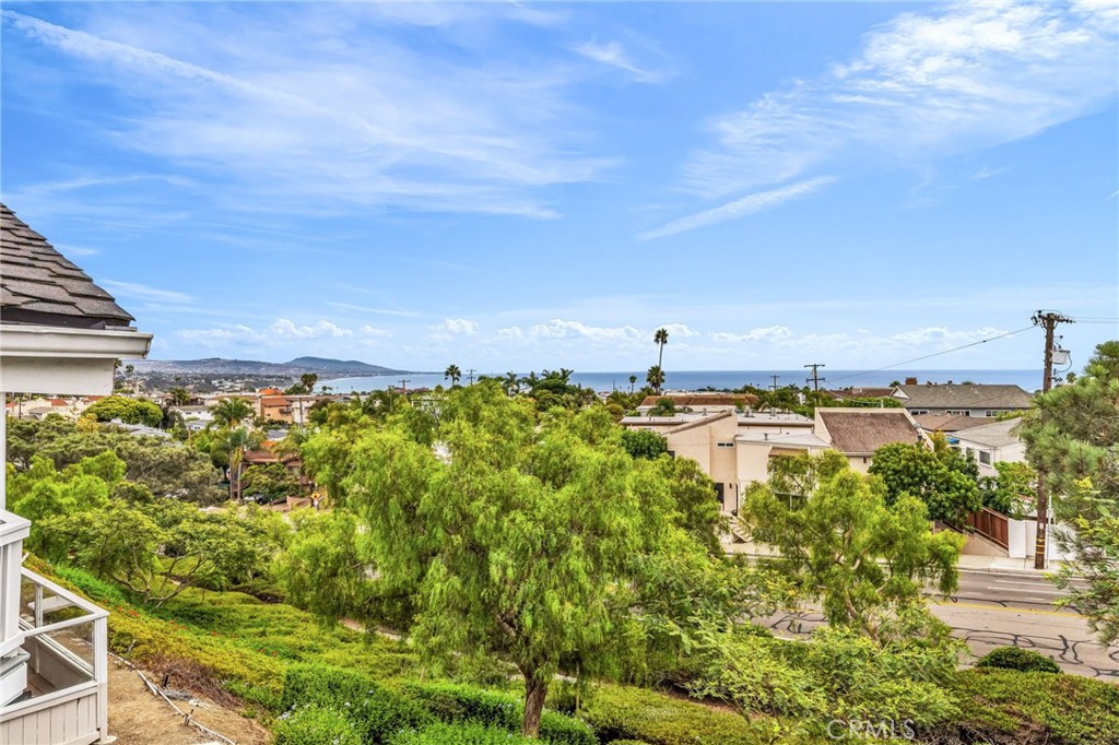 Perched in Dana Point’s sought-after, beach-close community of Sea Ridge, this exceptional residence captures sweeping ocean and coastline views. Step inside the main level to discover an airy, open-concept layout enhanced by soaring ceilings and abundant natural light. The living room invites you to unwind with sit-down panoramic ocean vistas, a cozy fireplace, and seamless access to a private balcony—perfect for soaking in golden sunsets. The adjacent dining area flows effortlessly into the bright, spacious kitchen, creating an ideal setting for entertaining. The main level also features a comfortable bedroom and full bathroom. Downstairs, the primary suite awaits, complete with a beautifully updated en-suite bath showcasing dual sinks, a walk-in shower, and a modern soaking tub. The suite opens directly to a private patio, where you can relax with the refreshing ocean breeze and tranquil views. This level also includes a dedicated laundry room. Ideally positioned near the end of a cul-de-sac with no neighbors behind, the home offers enhanced privacy and uninterrupted vistas. Sea Ridge residents enjoy resort-style amenities, including tennis courts, a clubhouse, a sparkling pool and spa, and lushly landscaped greenbelts—all just minutes from Dana Point Harbor, downtown shops and dining, and world-class beaches and resorts.