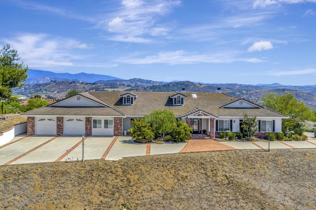 TRANQUIL, RIDGE-TOP CUSTOM-BUILT HOME with unparalleled panoramic sunrise AND sunset views from nearly every room in the house. Majestic rolling hills and Palomar Mountain to the east and then there's sweeping views of rolling hills and the Sleeping Indian mountain formation to the west, bringing in the gentle ocean breeze. From the moment you ascend the long elegant driveway you’ll feel transported to your very own top-of-the-world private retreat. The views from this home are absolutely breathtaking and a MUST SEE! The gorgeous beveled-glass front door welcomes you into this expansive 4-bedroom home boasting beautiful high beam ceilings, as well as, an additional separate office/guest unit with its own entrance and kitchenette. This spacious home is ideal for entertaining with the generously sized kitchen alongside the welcoming family room, all of which flow gently into the formal dining and living rooms. Plus there’s a great perk with having fully-owned solar, TWO walk-in closets in the primary suite, spacious kitchen with walk-in pantry, induction oven, high ceilings, raised garden beds, lime and lemon trees, a gazebo perfect to enjoy the morning or even the afternoon views. With well over 2 acres of land, the possibilities are endless—you could possibly have your own avocado grove, swimming pool, ADU, workshop or just leave it the way it is and enjoy this magnificent property located just minutes to the 76 yet it feels like it’s in another world—peaceful and serene. This is a MUST SEE home.