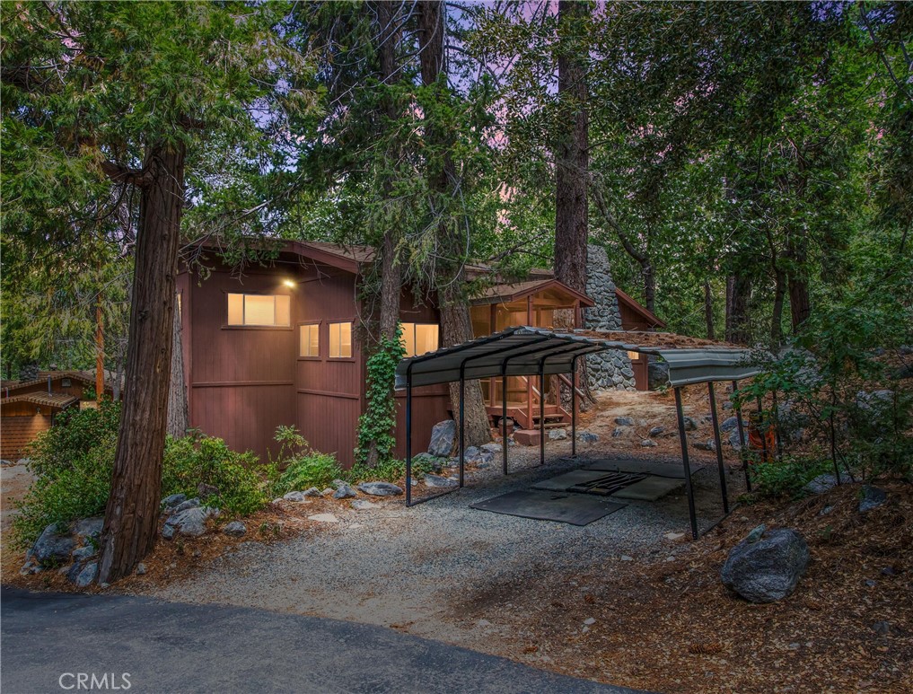 Nestled in the serene Big Pine Tract, this charming 2-bedroom, 1-bath mountain retreat offers peaceful living surrounded by stunning natural landscapes. Step inside to a warm and inviting main living area featuring vaulted cedar-lined ceilings, an open-concept kitchen, dining area, and cozy family room. Enjoy mountain evenings by either the wood-burning stove or fireplace. One bedroom is conveniently located on the main level, while the second bedroom is tucked away downstairs, accessible via a charming spiral staircase. Additional features include an indoor laundry area, detached carport, and a concrete patio—perfect for enjoying the crisp mountain air. Located in the Redlands Unified School District and just steps from beautiful hiking trails. HOA includes water, trash, and road plowing during the winter months. This is mountain living at its best—schedule your private tour today!