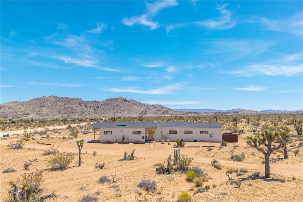*** Modern Desert Retreat on 2.25 Acres with Stunning Mountain Views***
Welcome to your dream desert escape! This beautifully designed modern single-family home, built in 2023, sits on 2.25 serene acres in a highly sought-after low-density neighborhood in Joshua Tree. With no electrical poles to interrupt your view thanks to underground utilities, you’ll enjoy unobstructed, panoramic vistas of the surrounding mountains and iconic Joshua Tree National Park. This 1,590-square-foot home is spacious and open with 3 bedrooms and 2 bathrooms, perfectly blending sleek design with warm, natural finishes. Whether you’re relaxing in the hot tub under the stars, resting in the hammock, or playing on the bocce ball court, every inch of this property is designed for comfort indoors and out. Watch the sunrise with a cup of coffee and toast to the sunset with a glass of wine, all from your private oasis. The home is a proven performer on Airbnb, boasting five-star reviews and earning the coveted Guest Favorite badge—ideal for buyers looking to continue its successful vacation rental legacy or enjoy it as a peaceful full-time residence. This home also has owned-solar photovoltaics and an electric car charger. Don’t miss this rare opportunity to own a modern desert gem with breathtaking views, privacy, and style. Come experience the magic for yourself!