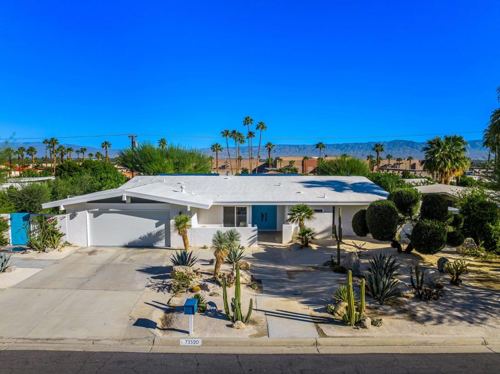 73520 Joshua Tree Street is a fully remodeled mid-century residence in South Palm Desert, nestled in a quiet, secluded neighborhood with sweeping mountain views and just blocks from El Paseo's premier dining, shopping, and cultural attractions. The home seamlessly combines modern finishes with carefully restored vintage details, preserving its architectural integrity while offering contemporary comforts for sophisticated desert living. Inside, polished concrete floors flow throughout the open-plan living, dining, and kitchen areas, which are anchored by a large kitchen island with eat-up seating, perfect for entertaining or casual gatherings. A dramatic wall of glass opens these spaces to a raised backyard terrace, creating a seamless connection between indoors and outdoors and framing scenic mountain vistas. Thoughtful spatial planning enhances both flow and privacy, ensuring that each area of the home feels purposeful and inviting. The primary suite and den occupy one wing of the home, while two guest bedrooms are positioned on the opposite side, providing separation and privacy. Multiple rooms open to patios or terraces, reinforcing the home's bungalow-like ease and celebrating the hallmark indoor-outdoor lifestyle of Palm Desert living. The tiered backyard is designed as a private retreat and entertainer's playground. A pool and spa are complemented by 2 outdoor showers, a fire pit, outdoor sauna, and expansive terrace spaces for lounging or dining al fresco, all surrounded by mature, low-maintenance landscaping. Additional highlights include a fully finished two-car garage with epoxy floors, restored original front doors with bronze hardware, owned solar, and a cohesive blend of modern and vintage design elements that convey a refined sense of style. Blending timeless mid-century character with contemporary sophistication, this residence offers elevated design, thoughtful indoor-outdoor integration, and easy access to El Paseo's lifestyle amenities, making it an exceptional opportunity for those seeking refined desert living in a serene South Palm Desert setting.
