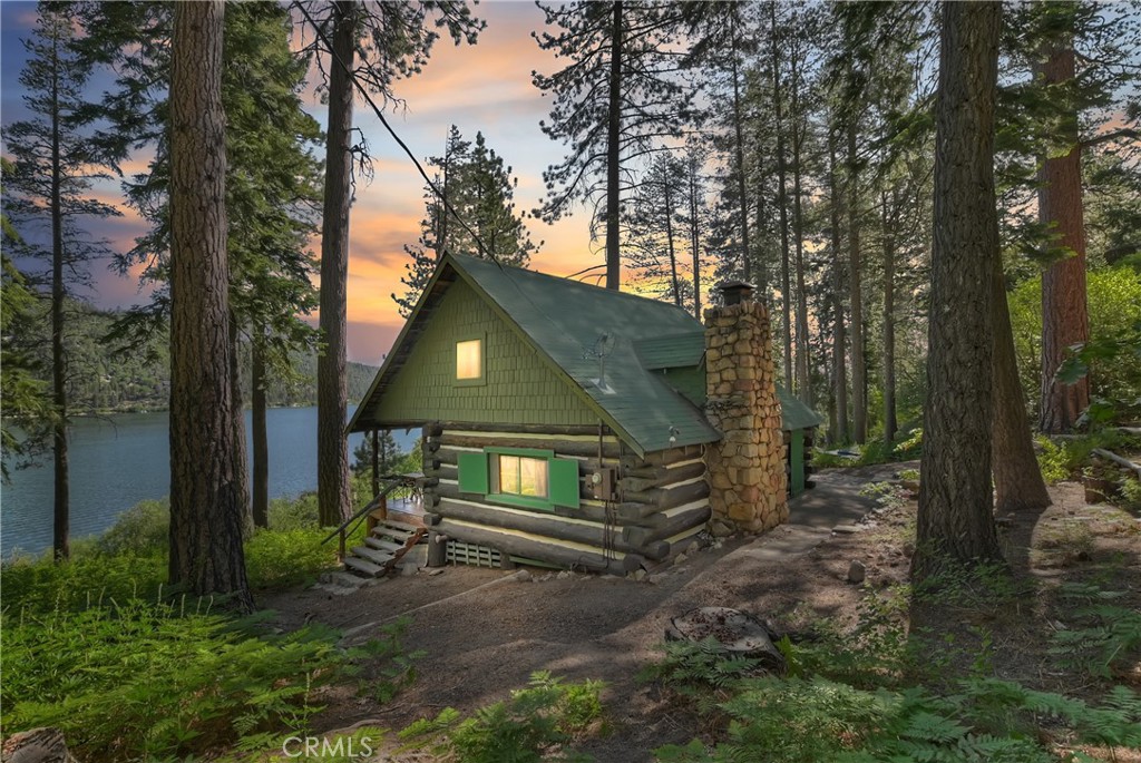 RARE LAKEFRONT OFFERING. Wait until you see this historic government lease cabin built by William Knickerbocker (c. 1920) with improvements that include an authentic whole log constructed cabin with one bedroom, a large second story bedroom, two bathrooms (3/4 or 1/2), a real rock fireplace, a spacious covered deck, your own assigned dock slip and a detached guest house with a "Vermont Castings" wood stove heater. All this is situated on a large lakefront footprint with a spectacular setting of tall pines and fern-covered grounds, offering a breathtaking view of the lake.
