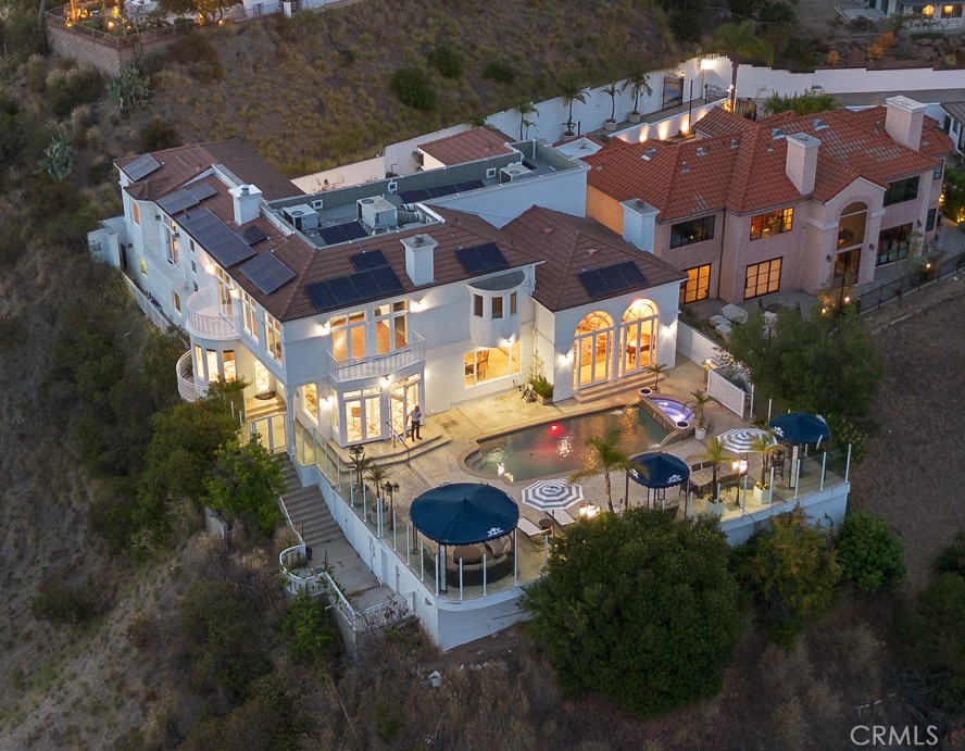 Nestled at the end of a private gated cul-de-sac in prestigious Glendale, 759 Foxkirk Rd represents an extraordinary opportunity to own over 5,700-square-foot architectural tour de force on nearly half an acre of meticulously landscaped grounds. This custom-designed estate, held by only its second owner for over two decades, offers an unparalleled combination of sophisticated luxury, breathtaking views, and ultimate privacy just minutes from downtown Los Angeles. From the moment you enter through the private gates, this Mediterranean-inspired masterpiece captivates with its soaring 30-foot ceilings in the marble entry foyer and a magnificent grand spiral staircase that serves as the home's centerpiece. For ultimate convenience and accessibility, a private elevator provides seamless access between all levels of the home. Nearly every room frames panoramic vistas of downtown Los Angeles and Glendale, creating a living gallery where city lights become your evening entertainment and mountain backdrops define your daily experience.
The main level flows seamlessly for grand-scale entertaining, featuring 21-foot ceilings in the living room, dining room, and family room. Floor-to-ceiling windows throughout maximize the spectacular views while flooding interiors with natural light. Rich hardwood floors and imported marble stone create an elegant foundation throughout, reflecting the impeccable attention to detail that defines this property.The spectacular master suite offers a true retreat with panoramic views from every window, creating a sense of floating above the city. The suite features a cozy fireplace for intimate evenings, a luxurious jacuzzi tub for ultimate relaxation, and an expansive walk-in closet that rivals the finest boutiques. Every detail has been carefully considered to create a private sanctuary within this exceptional home.The newly remodeled pool and spa create a private resort experience in your own backyard, perfectly positioned to capture both mountain and city views. The outdoor spaces have been designed as natural extensions of the interior living areas, providing multiple venues for alfresco dining, poolside relaxation, and outdoor entertaining against the dramatic backdrop of the Verdugo Mountains.