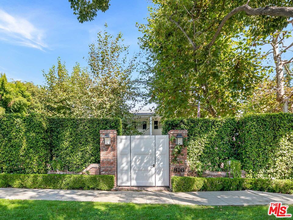 Located on approx. 1/2 acre lot in the desirable 800 block of the west end of the Flats, this beautiful Paul Williams inspired traditional estate features warm and sophisticated interiors and timeless architectural details. Set behind gates and a canopy of lush landscaping, the property is extremely private and includes 5 bedrooms, 6 bathrooms & a detached guest house/gym. The thoughtfully curated, open floor plan beams with natural light through bright picture windows and offers rich custom moldings & bespoke millwork throughout. An elegant formal dining room with easy access to the chef's kitchen & butler's pantry, sunken living room, library lounge with built-in bar and a large family room with breakfast nook & separate staff quarters, are all seamlessly connected to the expansive backyard. Upstairs, the primary suite overlooks the residence grounds & includes a refined entry foyer, private living area, luxuriously-appointed dual bathroom & double walk-in closets. Three additional, spacious bedrooms with en suite bathrooms are located upstairs, along with a cozy hallway library nook. Enjoy the tranquil outdoors with multiple lounge/entertainment areas, encompassing the pool, spa, outdoor BBQ/kitchen, dining area & park-like grassy lawn with play area. A true entertainer's dream home with an ideal layout for all kinds of family fun.