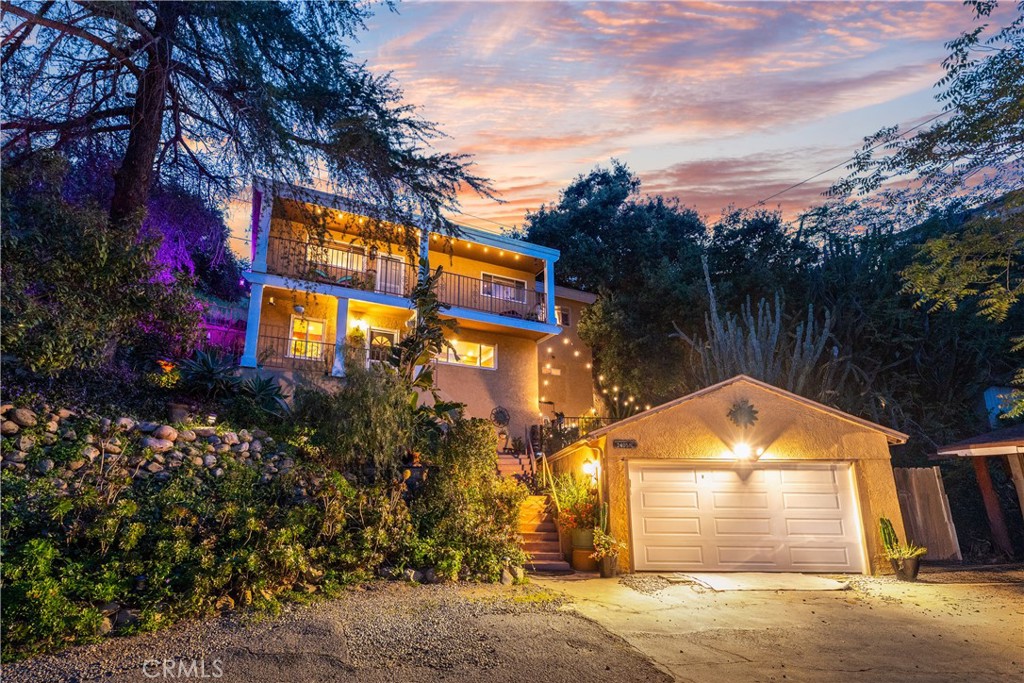 Escape the city and head down a long private road until you reach 24058 Eagle Mountain Street, a secluded hillside retreat tucked away on one of the largest and most unique lots in West Hills. This expansive 69x200-foot parcel (over 13,800 sq/ft) offers incredible privacy, panoramic canyon views, and room to grow. Peaceful and serene, yet full of everyday convenience, this property is a rare opportunity for those craving both nature and functionality.
The massive lot is a true showpiece, filled with lush, low-maintenance landscaping and a vibrant variety of native succulents that thrive year-round, adding color and charm to the grounds with minimal upkeep. Beyond aesthetics, succulents retain moisture, making them an eco-conscious addition that may help slow fire spread and enhance resilience in hillside settings. This expansive outdoor space not only feels like a botanical garden but also creates several distinct gathering zones throughout the property. The side yard features a dedicated dining area and a bonfire setup next to the detached shed, while the fenced backyard offers the perfect space for pets, entertaining, or simply soaking in the stillness under the stars. As you enter the front door of this charming two-story 3-bedroom, 2-bathroom home, you’ll find a kitchen with a large center island, recessed lighting, and original wood beams that flow into the living space to create a warm, open layout. All bedrooms are located upstairs, offering privacy from the main living areas. A full guest bathroom is tucked behind the kitchen for convenience, and across that hallway sits the laundry room, all on the main floor. Step out to one of the elevated balconies to take in sweeping views and fresh air. The 0.32-acre lot also includes outdoor space for RV parking or 4 vehicles, a detached shed, and a detached garage with air conditioning. This extra air-conditioned space isn’t included in the 1,524 sq/ft of living area and can serve as a gym, studio, office, or workshop. With county water and sewer already connected, you’ll enjoy reliable utilities without septic concerns. Lovingly maintained and thoughtfully updated with a newer roof and AC system, this home blends original 1940s charm with modern essentials in a quiet setting with no rear neighbors. Whether you’re seeking a peaceful escape or a versatile retreat, this West Hills gem delivers. Schedule your private showing today and make this hillside property your home.