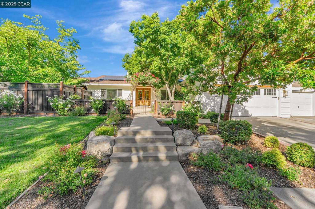 A rare single-level opportunity in one of Danville’s most desirable neighborhoods, this beautifully updated 4-bed, 2-bath home in the sought-after Greenbrook neighborhood sits on a spacious corner lot and offers a functional layout with quality finishes throughout. Inside, find new wood flooring, recessed lighting, and custom wainscoting at the entry. The remodeled kitchen includes a large center island, 6-burner gas range with custom hood, open shelving, gold finishes, beverage fridge, and a built-in desk area ideal for homework. The hall bathroom is updated with tile flooring and a shower-over-tub, and the primary bathroom features dual sinks and beautiful wood cabinetry. Outside, enjoy an amazing backyard retreat with an enormous pergola covering main hangout areas, a built-in firepit, overhead heaters for chilly nights, sliding barn doors hiding an outdoor TV, lush green grass, and an outdoor kitchen complete with counter space and a built-in grill. Direct access to the greenbelt adds even more outdoor space and privacy. Conveniently located near top-rated Greenbrook Elementary, the Greenbrook pool and tennis club, the Iron Horse Trail, and just minutes from downtown Danville.
