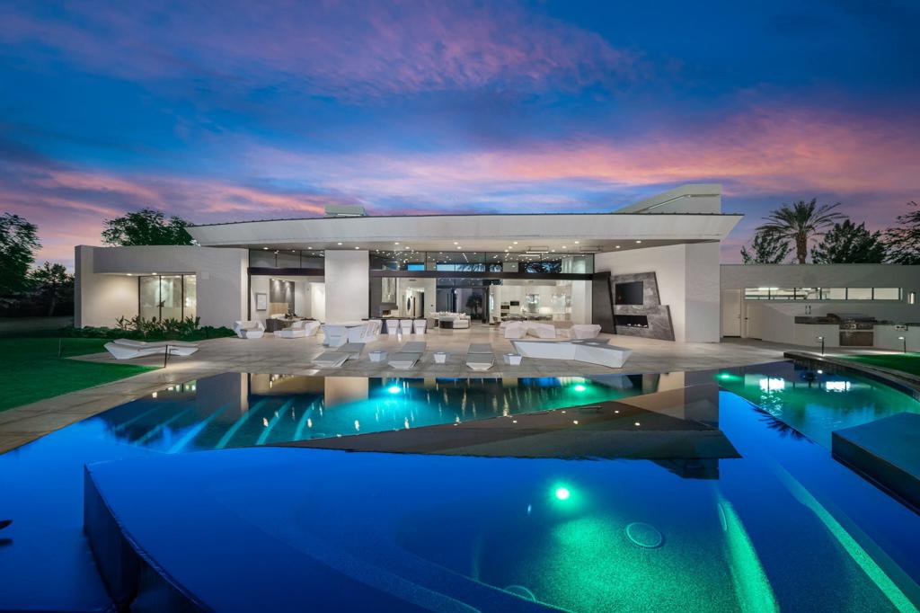 Spectacular, sprawling family compound located behind the gates of The Madison Club. This is the ultimate desert retreat with 3 bedrooms in the main home plus a luxurious home theatre, home office, guest den, wine cellar, and expansive indoor/outdoor home bar. A massive bookended marble slab fireplace warms the great room with floor to ceiling sliding glass doors framing the views of the snowcapped San Jacinto mountains. The great room flows into the covered patio overlooking the 4th hole on the prestigious Tom Fazio designed course with a Zero edge pool, sun deck and opulent fire features. The primary bedroom suite has a magnificent marble fireplace feature wall. The spacious guest home features 3 bedrooms, 3 baths, kitchen, living room with sliding glass pocket doors leading out to its own pool, spa, fire features and sun deck. Behind the private gates of this compound is a wonderful park like setting with open grass area and a playground for the children or grandchildren to enjoy. The home may be sold with or without the adjacent grass lot.