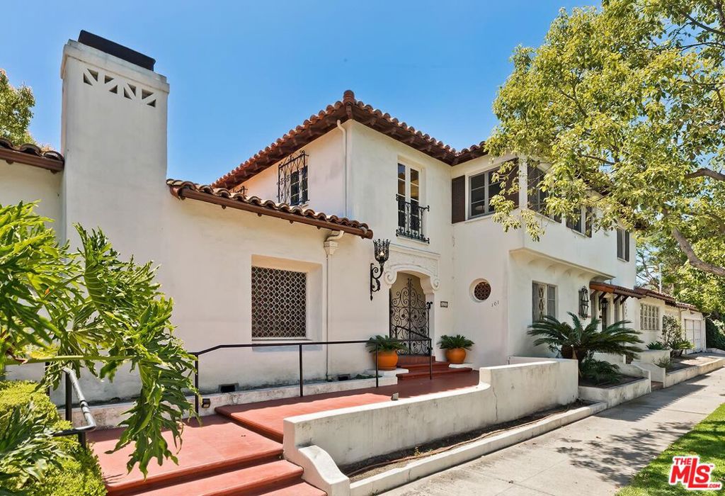 This truly rare 4400+ sqft 1928 Spanish Colonial Revival home with extraordinary original details is the crown jewel of this coveted Beverly Grove enclave. Set on an expansive 9200 sqft corner lot in the premiere location of the Miracle Mile North HPOZ, this estate offers authentic period architectural elements such as carved wood doors, ornate ironwork, stained-glass windows, intricate moldings, detailed plaster work, beamed ceilings, Saltillo tile, and hardwood floors. The tiled entry leads to a ballroom-sized living room with commanding stone fireplace and detailed coffered ceilings. The equally beautiful dining room with another dramatic ceiling opens to a romantic tiled courtyard, perfect for indoor-outdoor entertaining. The sunny breakfast room features original built-ins and more French doors opening to the backyard. A large kitchen with tons of storage, laundry room, paneled library, and a powder room complete the main level of the residence. A dramatic staircase with wrought iron railings and a massive stained-glass window leads you upstairs to four spacious bedrooms with gleaming wood floors and three full baths. The backyard is an oasis featuring beautiful plantings, large pool, tiled patio, and charming fountains. An additional two-room guest suite with bath and separate entrance provides flexible options for a home office, mother-in-law suite, artist studio, or children's playroom. A three-car garage and California basement provide for ample parking and storage. Recent upgrades include all new HVAC system, new electrical panels, newer sewer line, new drain lines, partial new roof, and two new showers. Close to the Farmers Market, Grove, houses of worship, and the vibrant shopping and dining of the Miracle Mile.