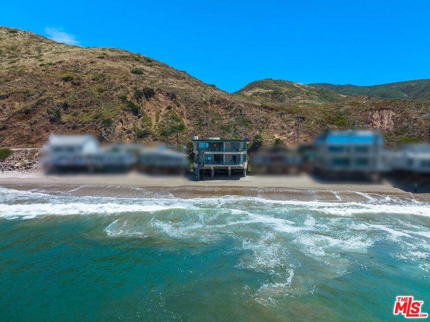 Designed by architect Michael Barsocchini, this Malibu beach house is a contemporary masterpiece envisioned for oceanfront tranquility and truly impressive entertaining, located on one of Southern California's extremely rare private sandy beaches.  Just past the break at County Line, the timeless two-level residence is perched above the sand on concrete caissons with a fortified seawall.  Commanding 70 feet of beach frontage, the home has panoramic views of whitewater, ocean, and islands, dolphins, sea birds, and sunsets that can be enjoyed from grand interior spaces and full-width decks on both levels.  From the moment you enter the front door, the ocean is on view: an ever-changing wall-to-wall artwork.  The formal living room, complete with fireplace and wet bar, has a wall of accordion doors that fold open to the oceanfront deck for indoor-outdoor entertaining.  A private spiral staircase leads to the beach two levels below.  Also on this floor is a full bath, a bedroom that opens to the oceanfront deck, and an en-suite bedroom with ocean views.  Echoing the form of the spiral staircase on the beach side of the house, an interior spiral stairway sits in an atrium beneath a large round skylight.  This leads to the lower floor, where the kitchen, dining area, and lounge share magnificent ocean views and another wide deck with accordion doors.  The serene primary suite also opens onto a beachfront balcony and has a walk-in closet and a lovely, updated spa-style marble bath.  There is an additional bedroom, another full bath, and a laundry area on this level.  The lower level opens to a grass garden courtyard with BBQ area.  With an attached garage and generous guest parking in the driveway, this handsome beach house is the perfect year-round getaway.