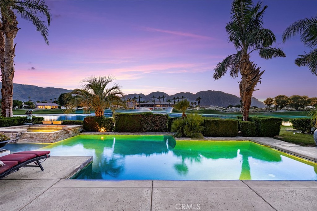 Undeniably the absolute best location in PGA WEST!!! VIEWS! VIEWS! VIEWS! Welcome to 56102 Baltusrol, La Quinta – where elevated desert living meets unforgettable views. Perfectly situated on the 9th and 18th holes of the prestigious Nicklaus Tournament Course at PGA West, this stunning home captures panoramic vistas of the lush fairways, sparkling lake, iconic clubhouse, and the dramatic Santa Rosa Mountains. As you walk through the elegant steel privacy door you are greeted by a charming, beautifully landscaped courtyard that welcomes you as you approach the front door—setting the tone for the tranquility and elegance that await inside. Designed with style and sophistication, this 4-bedroom, 4-bathroom retreat features polished concrete floors, soaring 12-foot ceilings, and an open-concept layout that flows effortlessly from room to room. Walls of glass flood the home with natural light and seamlessly connect the indoor space to the outdoors. Step outside to your own private oasis—complete with a sparkling heated pool and expansive patio—ideal for entertaining, relaxing, and soaking in the breathtaking scenery. Whether you’re enjoying morning coffee with a sunrise over the view of the lake or watching the sunset paint the mountains in golden hues, every moment here feels like a resort getaway. This home delivers the ultimate in resort-style living. A golfers paradise! Don’t miss your chance to own this one-of-a-kind property in one of La Quinta’s most prestigious communities. Welcome to the good life at PGA West. Membership is available.