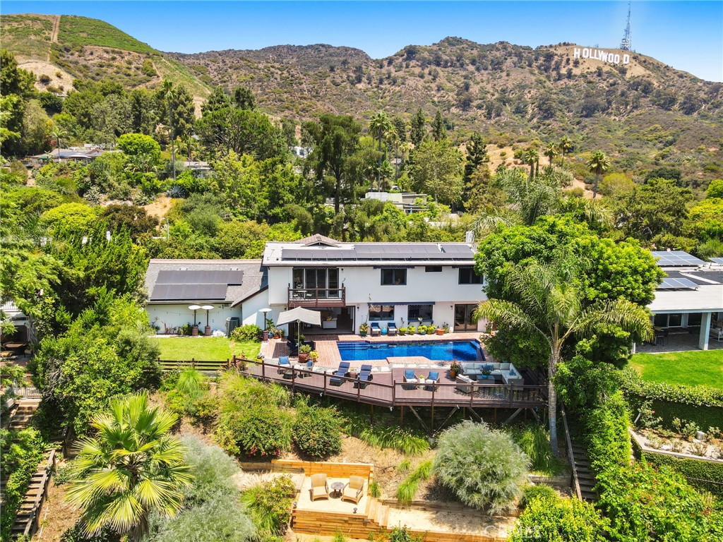 Perched high above the city lights with commanding views of the Hollywood Sign and the shimmering waters of Lake Hollywood, 6312 Tahoe Drive is a private sanctuary that blends timeless style with modern California luxury in Lake Hollywood Estates. This four-bedroom, three-bathroom residence offers an inviting and elevated lifestyle, just moments from the vibrant pulse of Hollywood’s studios, shopping, dining, and entertainment.
The living room is bathed in natural light, with soaring ceilings that create a sense of openness and grandeur. Dual-pane, wood-trimmed windows frame panoramic vistas throughout the home. The recently remodeled kitchen features sleek marble countertops and modern finishes, connecting seamlessly to the formal dining room, ideal for hosting and everyday living. A cozy den opens directly to the backyard, where an in-ground pool adorned with mosaic tile, an above-ground spa, and a fully equipped outdoor kitchen create a true resort-style escape.
Terraced outdoor spaces offer multiple private areas designed for relaxation and enjoying breathtaking sunsets over the lake. The floor plan includes a convenient downstairs bedroom and full bathroom, offering privacy for guests or a flexible home office. A three-car garage provides generous storage and parking, while a fully owned solar system brings sustainable living to this stylish hillside retreat.
Sophisticated, secluded, and located in one of Los Angeles’ most iconic neighborhoods, this is a home that captures the essence of Hollywood living with privacy, comfort, and unforgettable views.