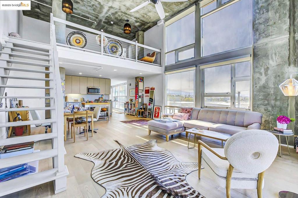Stop your search. The one you’ve been waiting for is here! Welcome to a spectacular corner loft where the sheer volume of the space and the incredible light are the true stars. This is your personal celestial theater, offering breathtaking views of the sunrise, sunset, moonrise, the Oakland Hills and the estuary. This home’s genius lies in its flexibility. With two full baths, one bedroom and multiple modular spaces, the layout is your canvas. The expansive entry is perfect for a home office, or library while the versatile mezzanine could be your meditation space or yoga studio. It’s loft living, perfected. The best part? The heavy lifting is done. We're talking 26 brand-new windows with custom shades, a fresh coat of paint, and more. All you have to do is move in and start living your best life. Effortless commutes via BART, Amtrak, and the SF Ferry. Weekend walks along the sparkling waterfront. An endless supply of amazing coffee, food, and wine just steps from your door. Plus, you have security and access to the building's gym, sauna, pool and business center. This isn't just a home; it's a launchpad for an incredibly luxurious Oakland lifestyle.