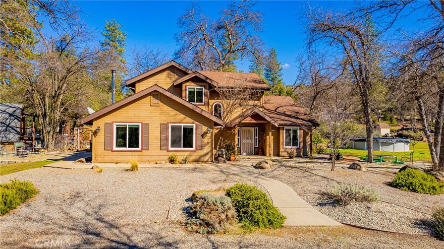 Nestled in the scenic Sierra foothills near Yosemite National Park & just minutes from the sparkling waters of Bass Lake, this warm & welcoming mountain retreat is the perfect family home or vacation getaway. With spacious living areas, rustic charm, and modern comforts, it's built for gathering whether around the wood stove on snowy nights or the patio on summer afternoons. Surrounded by pines & peaceful skies, enjoy year-round outdoor recreation, small-town charm, and the timeless beauty of nature right outside your door. Updates include new furnace/air conditioning, windows, hot water heater, wood stove in living room, new kitchen, new laundry room & door, new flooring on main floor, newer vanity to upstairs bath, expansion to the outdoor concrete patio & above ground pool. Separate garage/shop area with bonus studio with 3/4 bath upstairs. Large carport for your RV parking. Private well with storage tank & new booster pump. Enclosed garden area, green house & storage shed. Lovely usable property perfect for the family to enjoy and make wonderful memories.