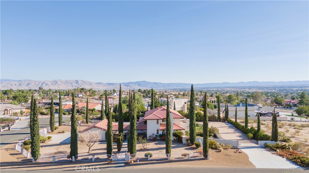 View! View! View! Spectacular Custom Home in Apple Valley
Nestled at the end of a peaceful cul-de-sac, this stunning custom-built home sits on a generous 38,500 sq ft corner lot with sweeping valley views. Offering 3,674 sq ft of refined living space blends timeless Spanish-style architecture with modern comfort and luxury. The home features 3 bedrooms, 2.5 bathrooms, a formal dining room-perfect as a flex space, a private office-potential 4th bedroom, and an oversized 4-car garage. Enter through a charming arched walkway and double glass doors into a light-filled interior with elegant tile and hardwood floorings, soaring arched windows, warm tones, and a cozy fireplace that adds character and sophistication. The chef’s kitchen is designed to impress-featuring Corian countertops, a farmhouse sink, prep sink on a large center island, Viking appliances, and a wet bar with wine cooler-flowing seamlessly into the family room and breakfast area. Upstairs, a custom wood spiral staircase adorned with Spanish-style tilework leads to the luxurious primary suite, where a private balcony reveals breathtaking valley views. The spa-inspired bathroom includes a large soaking tub, walk-in shower, dual vanities, and a walk-in closet. Two additional bedrooms provide abundant natural light and views, while the spacious laundry room and enclosed patio with a second wet bar enhance everyday comfort. Step outside to a serene Spanish-style courtyard surrounded by cypress trees, fruit trees, and mature shrubs-an ideal setting for relaxing or entertaining. Located in one of Apple Valley’s most desirable neighborhoods, this one-of-a-kind custom home offers exceptional space, charm, and unforgettable views.