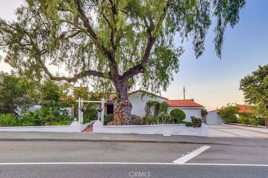 Charming single-level home perfectly situated in the desirable Red Tile Roof neighborhood of Miraleste. Step inside to find warm cherry hardwood floors and abundant natural light streaming through Andersen windows. Both the living room and primary bedroom open through sliding glass doors to an expansive patio, where sweeping canyon and city views set the stage for unforgettable entertaining or peaceful evenings under the stars. A serene water feature in the side yard, visible from the living room, enhances the sense of peace and harmony that defines this home. The kitchen features granite countertops, tile flooring, a double oven, and a professional-grade six-burner stove. The guest bathroom has been enhanced with a newly installed double vanity, bringing both convenience and style. Beyond the interiors, the grounds are a lush sanctuary. An edible landscape of peach, apple, guava, lemon, pomegranate, avocado, fig, pear, and mulberry trees, along with vibrant lemon grass, provides a fragrant, colorful, and fruitful setting year-round. The front gardens deliver striking curb appeal, while the expansive side yard and driveway allow ample room for recreational toys or additional vehicles. Home exterior and interior freshly painted throughout includes forced air heating and cooling and is only a 5 minute walk to the Miraleste Plaza.
