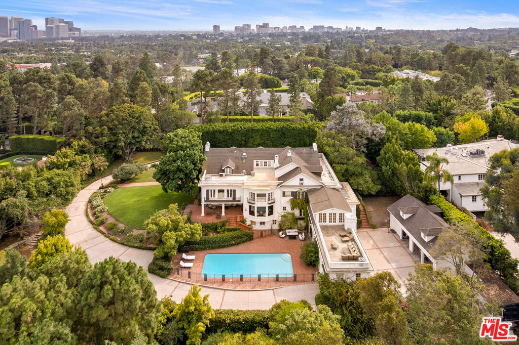 Iconic Beverly Hills Legacy EstateA Rare Opportunity to Own a Landmark Southern Colonial on Over 1.5 AcresSet behind gates on one of the most prestigious cul-de-sacs in Beverly Hills, this extraordinary Southern Colonial estate is a timeless masterpiece of elegance and grandeur. Originally built in 1911, the residence is a treasured part of Beverly Hills historygraciously perched on a knoll and surrounded by 1.5 acres of verdant, manicured grounds with scenic treetop views.With over 8,400 square feet of living space, this grand estate seamlessly blends historic charm with modern luxury. The stately front faade is enhanced by a large covered veranda, leading to a sweeping entry foyer that introduces a series of stunning public roomseach with soaring ceilings, intricate moldings, and French doors that open to tranquil patios and gardens.Highlights include: A formal living room of exceptional scale, an incredible dining room with seating for 20. A large wood-paneled library rich in character and a gourmet kitchen featuring soapstone counters, custom cabinetry, Sub-Zero refrigeration, 60" Wolf range, double ovens, and dual dishwashersThe primary suite is a private sanctuary with high ceilings, a marble-clad bath, a cozy sitting area, and a fireplace. Additional accommodations include three generous en suite bedrooms, a den with fireplace, a separate staff wing, gym, playroom/bonus rooms, and a large guesthouseideal for extended stays or entertaining.Outdoor amenities are equally impressive: expansive lawns, quiet patios, a sparkling pool, BBQ area, and mature landscaping offer an idyllic retreat in the heart of the city.This is more than just a homeit's a legacy. A rare opportunity to own one of Beverly Hills' most iconic estates, rich in history and timeless in appeal.