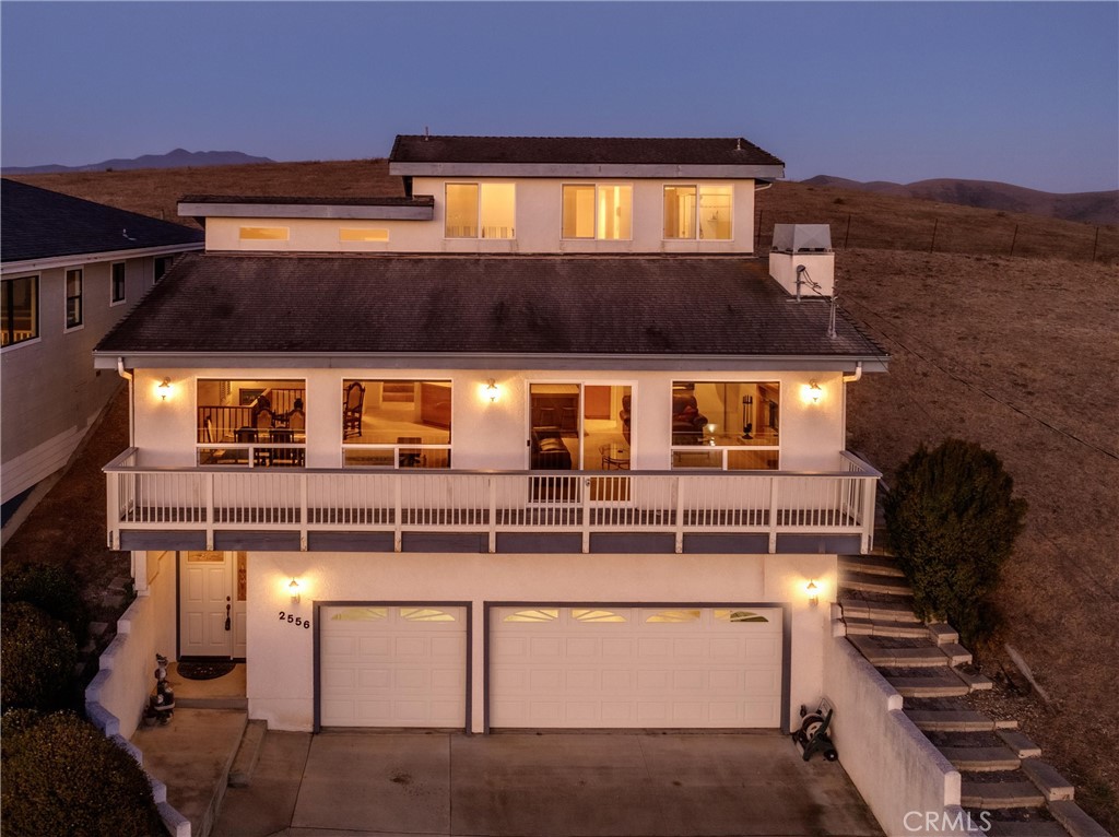 Spectacular panoramic ocean views stretch from Cayucos to Montana de Oro with peaceful ranch land behind—truly the best of both worlds. This 3-bed, 3-bath, 2,200 sq ft home boasts an open floor plan where the kitchen flows effortlessly into the living spaces, complete with a large prep island, tiled wrap-around breakfast bar, pantry, and ample cabinetry. The living room features a cozy fireplace, soaring ceilings with recessed lighting, corner windows framing iconic Morro Rock, and sliding doors leading to a view deck. Spacious enough to accommodate both casual lounging and a formal dining table, the living area is designed for entertaining. The primary suite lets you watch whales from bed, with a spa-like bath offering dual sinks, a soaking tub, and walk-in closet. A secondary en suite also captures ocean and Rock views, while the third bedroom is conveniently located near the third full bath. Extras include an oversized three-car garage, individual laundry with folding station, and low-maintenance stucco exterior—an ideal blend of comfort, design, and coastal lifestyle.