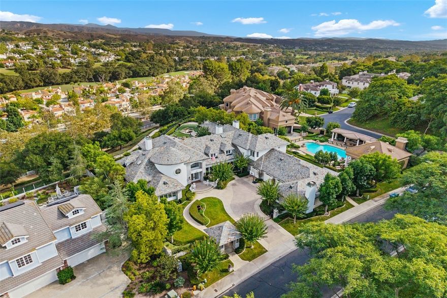 Experience refined living in this exceptional custom estate tucked within the prestigious, guard-gated enclave of The Woods at Coto de Caza. Set behind its own private gates on an expansive 1.11-acre homesite, this residence offers unmatched elegance, privacy, and breathtaking views. With 7 ensuite bedrooms and 8 bathrooms, the versatile floor plan includes three main-level suites, one being a private attached casita with full kitchen—perfect for extended guests or multi-generational living.
Inside, a dedicated executive office inspires productivity, while soaring double-height coffered ceilings, designer finishes, and walls of glass create a sense of grandeur. The bright chef’s kitchen boasts white cabinetry, quartz countertops, white appliances, and a picture-perfect window framing sweeping hillside views. An impressive climate-controlled glass wine wall serves as a centerpiece, elevating the open-concept living and dining spaces.
Designed for effortless indoor-outdoor living, the folding glass wall opens to a resort-style yard featuring a sparkling pool, covered outdoor living room with barbecue, and custom putting green—all embraced by privacy and stunning vistas. A 4-car garage completes this extraordinary estate, offering the best of luxury and seclusion in one of Coto de Caza’s most coveted neighborhoods. Come join the Coto de Caza Golf and Racquet Club, or the Equestrian Center. The public and private schools in this area are top-notch! This is your opportunity to enjoy the communities hiking trails, basketball courts, baseball fields, playgrounds and dog park. Don't pass up this opportunity to live your best life here at 22 Palomino!