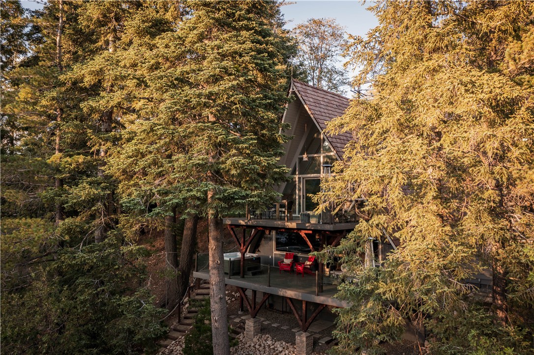 Discover this beautifully remodeled lakefront retreat tucked away on one of Lake Arrowhead’s most sought-after streets. With sparkling lake views, designer finishes, and a private single-slip dock (Dock #S26), this 3,720 sq ft home offers the perfect blend of modern luxury and mountain charm. Step inside to a bright, open-concept double A-Frame with expansive windows and fluid outdoor spaces. The main-level great room centers around a dramatic stone fireplace with the lake as the backdrop and sliding doors opening onto an entertainer’s deck overlooking the water. The gourmet kitchen features high-end appliances, a large island, built-in dinning banquette and adjacent BBQ patio—ideal for hosting gatherings year-round.
The spacious main-floor primary suite boasts serene lake views and a spa-inspired en-suite bath with a floating tub with views of the water. Upstairs, two guest bedrooms, each with a-frame architecture, share an interior water-view balcony, while the lower level includes a fourth bedroom, full bath, laundry room, and an incredible media/game room with surround sound and built-in bar—perfect for cozy nights or lively weekends.
Enjoy multiple decks, a covered patio with a hot tub, and direct access to Lake Arrowhead’s clear waters. The property includes off-street parking for four vehicles, dual Tesla charging stations, a whole-house generator, central air conditioning and a security camera system for ultimate comfort and peace of mind.
Located just minutes from Lake Arrowhead Village and year-round recreational opportunities, 161 Rocky Point Rd is your private escape—whether as a full-time residence, weekend getaway, or luxury rental.