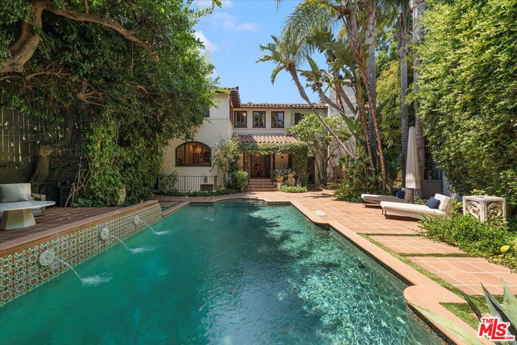7040 Hillside is a piece of Hollywood's golden era. This Spanish Revival beauty was designed in 1925 by architect-to-the-stars, Marshall P. Wilkinson and lovingly updated for modern living. Walled and gated for privacy, this home exudes quiet elegance. Enter into a soaring two-story foyer with painted beamed ceiling and the first of the beautiful wrought iron work featured throughout. The generous step-down living room offers a wood burning fireplace and French doors to the stunning back patio. The dining room is separated by columned arches. The kitchen features top of the line appliances, Wolf, Sub-Zero, Bosch. Upstairs, the large, airy primary bedroom offers abundant light and a beautifully appointed en suite bath. The second bedroom suite offers a separate lounge room. A shared bathroom serves it and the third bedroom, currently used as an office. A small downstairs room can be a wine cellar or small gym. The spectacular back patio features a classic pool, surrounded by lounging areas, fountains, outdoor dining, and a built in fire pit. The mature surrounding landscape offers utmost privacy. This is a true sanctuary in the heart of the busy city, convenient to everything yet feeling a world away. Welcome home! (Be sure to click on the Virtual Tour and Property Website buttons above.)