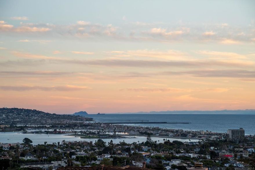 Panoramic ocean, bay, and coastline views abound from this recently renovated soft-contemporary home in Los Altos Estates, a discrete and gated enclave of eight luxury homes on the sunny side of Mount Soledad. Captivating sunsets and blue water are visible from all of the primary entertaining and living spaces in this home, and an open floor plan with an expansive wrap around terrace allows living, dining, and cooking to flow seamlessly together on the entry level. Home features 4 bedrooms, 3.5 bathrooms, and 2 bonus rooms which are currently used as fitness and theater rooms. The primary suite, also on the entry level, enjoys a private wing with sensational south and west views from bedroom, bathroom, and terrace. Views continue from the downstairs bedrooms and also from a lower fire pit lounge in the backyard. Nearly 17,000 sqft of land provides plenty of space to play and a future pool. Additional features include AC, owned solar, 3-car attached garage, large driveway, wine cellar, wet bar, and more. Shared amenities include a multi-sport court, pool, spa, and clubhouse. Los Altos Estates is a few blocks from Kate Sessions Park and 1.5 miles to the ocean.