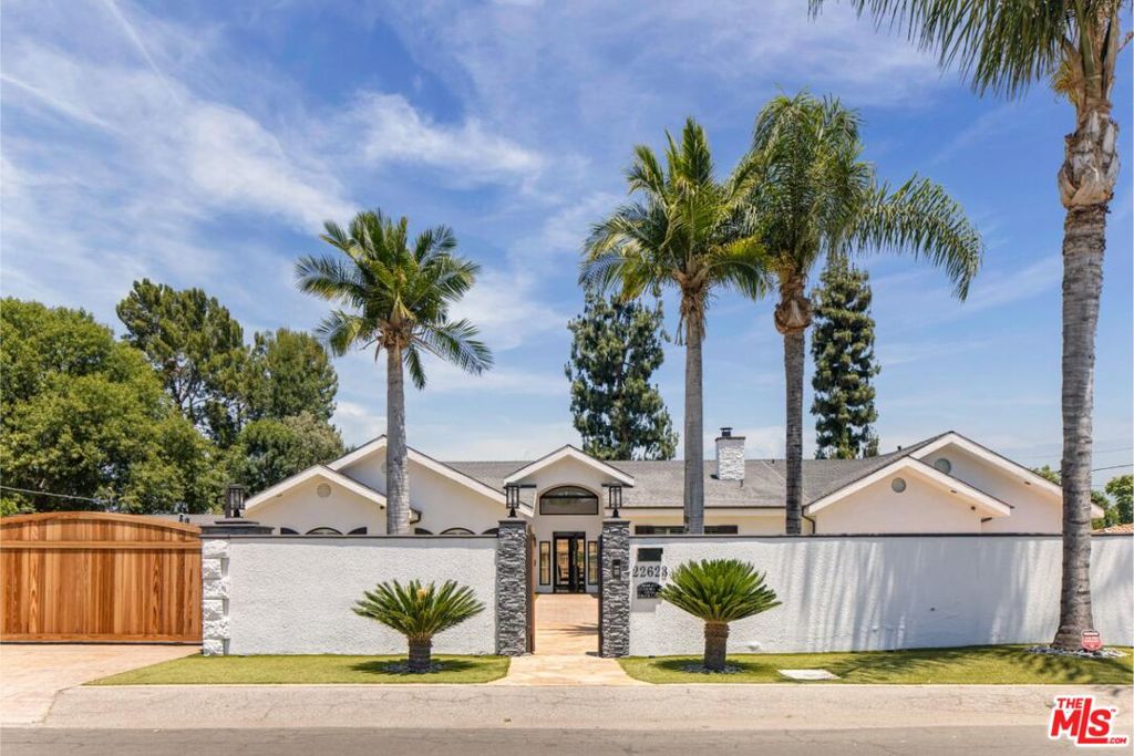 Behind gates and situated in a quiet Woodland Hills neighborhood, this sophisticated residence recently completed a thoughtful renovation. All on one story, and on a sprawling 18,000 square foot flat lot, this five-bedroom, four-bathroom home is nearly 4,000 square feet. It's conveniently located moments to the Topanga Village, Calabasas Commons, and the upcoming Rams Village. Additionally, the property falls within a well-regarded school district and walking distance to Shoup Park delivering a perfect balance of suburban comfort and city accessibility. Inside, the home features quality finishes, vaulted ceilings, and modern smart home upgrades, including surround sound, a whole-home water softening system, and solar panels for improved energy efficiency. The kitchen includes an oversized island and is well-suited for both daily use and hosting. The primary suite includes a spacious bathroom, walk-in closet, and direct access to the backyard. Accordion doors open to a private backyard with a pool, spa, waterfall, fire pit, LED lighting, palm trees, outdoor speakers, and a putting green designed for relaxed outdoor living. The three-car garage includes a finished ~400 square foot bonus room with an additional bathroom above, offering flexibility for use as a game room, office, or studio. Too many upgrades to include, however the complete list is readily available.