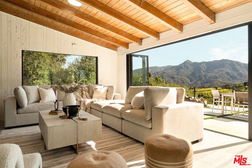 Remodeled Topanga compound retreat set on more than half an acre of fully usable land. Two separate street entrances provide effortless arrival and abundant parking for residents and guests. Indoor and outdoor living define the home. Fleetwood windows open the main living areas to expansive patios beneath open skies, framing sweeping views of the Santa Monica Mountains. A generous front patio sets the stage for al fresco dining and relaxed gatherings, while the pool enjoys its own private area away from the main living spaces, creating a serene environment for lounging or entertaining. Inside, the living room, dining area, and family room connect with natural flow, designed for both comfort and conversation. The cook's kitchen stands at the center with a large island offering plentiful prep space and storage. A vaulted wood ceiling crowns the family room, where windows capture the landscape and bathe the interiors in natural light. The primary suite is spacious and features a private bath with dual vanities, a soaking tub, an expansive shower, and a walk-in closet. Two additional bedrooms are located on the main floor alongside a full bathroom with an oversized shower. The lower level adds versatile space to suit your lifestyle. A lounge can serve as a media or game room and easily function as an additional bedroom if desired. A full bathroom is also on this level, along with a separate room with its own entrance, ideal for an office, studio, guest quarters, or extra storage. Outdoors, the grounds invite both relaxation and gatherings, whether by the pool, on the patios, or across the broad usable lot. Nearby are scenic trailheads and beloved local favorites, with convenient access to both the Westside and the Valley.