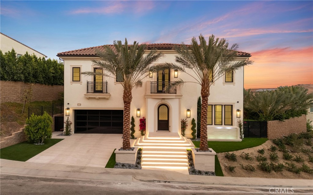 Experience luxury living in this original Palisades model home in the prestigious gated community of Westcliffe at Porter Ranch. Completed in 2021, this 5-bedroom, 6-bathroom residence sits on a rare 14,142 sq. ft. flat lot and offers some of the most breathtaking, unobstructed city and mountain views in the community. From the moment you arrive, the home impresses with Italian stonework across the driveway and entry, illuminated step lighting, and tranquil water features that set a sophisticated tone. Inside, a grand foyer with soaring ceilings and a designer chandelier frames the dramatic floating staircase and European oak hardwood floors. The open-concept design connects a spacious dining area to a chef’s kitchen with an oversized waterfall island, Sub-Zero refrigerator, Wolf appliances, Wolf coffee system, pot filler, and walk-in pantry. A sleek linear fireplace anchors the great room, while 20’ x 8’ glass pocket doors extend the living space outdoors for seamless entertaining. Upstairs, a loft-style family room separates each wing. The primary retreat serves as a true sanctuary, complete with a private balcony overlooking the San Fernando Valley, a spa-inspired bathroom with Calacatta marble counters, dual vanities, soaking tub, walk-in shower, and an oversized custom closet. Three additional en-suite bedrooms, each with large closets, complete the upper level. The backyard is both functional and inspiring, designed with brand-new turf, a covered patio with fireplace, and plenty of flat space for a pool, spa, outdoor kitchen, and more. Permitted pool plans with renderings are already in place for the next owner to create their dream outdoor oasis. Additional highlights include surround sound throughout, partially furnished interiors, solar panels that are fully paid off, and a direct-access 3-car garage. This residence combines timeless Palisades craftsmanship with today’s modern comforts, a rare opportunity to own one of Porter Ranch’s most desirable homes with head-on city and mountain views.