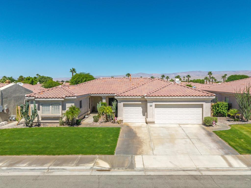 Welcome to Sonrisa in La Quinta! This beautifully maintained home, lovingly cared for by its original owners, offers over 2,000 sqft of comfortable living space with thoughtful upgrades throughout. Featuring 3 bedrooms, 2 full bathrooms, the layout includes an indoor laundry room with a wash basin that leads out to the large 3 car garage, an updated spacious kitchen with slab granite countertops and stainless steel appliances perfect for cooking, entertaining, or casual meals. Enjoy travertine flooring in the main living areas and plush carpeting in two of the bedrooms, and vinyl flooring in the third bedroom. Wood shutters throughout! The primary suite is a true retreat, boasting a permitted extra-large dream closet along with an additional walk-in closet and a spa-inspired main bathroom with a luxurious steam shower for ultimate relaxation. The dining area offers warmth and charm with a cozy fireplace and a built-in wet bar-ideal for entertaining guests. French doors lead you to the outside to the large, low maintenance backyard, complete with turf grass, offering a great space for outdoor fun, pets, or simply relaxing in the sun. Newer AC and heating units! Don't miss the opportunity to own this move-in-ready gem in the desirable Sonrisa Community of La Quinta!