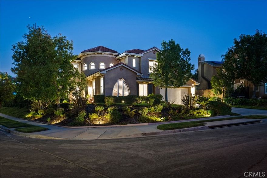 Welcome to this truly exceptional corner-lot residence in the desirable Brentwood community of Simi Valley, where elegance, comfort, and design come together seamlessly. The fully landscaped and beautifully illuminated lot features an array of vibrant plants and fruit trees, along with tiered backyard landscaping filled with lush, mature trees that create a private oasis surrounding the spectacular pool and spa with tranquil water features and custom lighting. Enter through a grand turret entryway with soaring ceilings and rounded walls that set the tone for the home’s distinctive Mediterranean/Spanish-inspired architecture. The formal living room showcases a unique picture window and a stunning curved staircase, while the formal dining room connects to a bar area and the expansive family room with dramatic high ceilings. The open-concept kitchen is a chef’s dream, complete with an oversized island with breakfast bar, Monogram six-burner gas stove, Sub-Zero refrigerator, warming drawer, convection oven, dishwasher, and under-cabinet lighting. The primary suite on the main level features dual closets and a luxurious soaking tub, accompanied by a guest suite with walk-in shower and a powder bath for visitors. Upstairs, a spacious loft anchors two large bedrooms with an extended Jack-and-Jill bath, plus another guest suite with its own full bath. Thoughtful upgrades include shutters throughout (including high-top windows and exterior doors), ADT security system, dual-zone HVAC, DC ceiling fans in all bedrooms, a three-car tandem garage with epoxy floors and 220V outlet for EV charging, and a large laundry room. With 5 bedrooms, 4.5 bathrooms, and every detail designed for beauty and functionality, this stunning home captures the essence of California living—luxurious, inviting, and unforgettable.