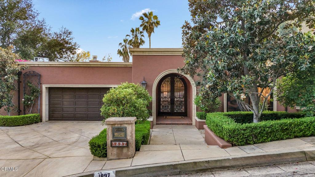 With its stunning architecture, coveted address in Upper Linda Vista, and beautifully-designed outdoor spaces, 1897 Braemar Rd is a secluded Pasadena treasure for those with discerning taste. Designed by esteemed Bel-Air architect Aleck Dugally, whose clients included Sylvester Stallone, Denzel Washington, and Sumner Redstone, this Contemporary Tuscan Villa stands apart with inspired details and a deeply peaceful setting. A grand foyer with a soaring ceiling offers an exquisite welcome. Sunlight pours in from the massive skylight overhead, illuminating the sumptuous travertine floors and offering a prelude to the elegance that awaits within. You'll instantly appreciate how Dugally's semi-open concept layout strikes the perfect balance between spaciousness and separation. The foyer adjoins both the dining room on the right and the sunken living room, which rests straight ahead. The latter offers the perfect setting for an intimate concerto or book reading. A chef-worthy kitchen features a cork floor, top-tier German appliances, and gorgeous wood cabinets. Wrapped in windows and boasting a radiant skylight, this dream kitchen overlooks the breakfast area-your sunlit spot for mindful mornings. Casual relaxation is always on offer in the inviting family room, which includes a large fireplace that creates the perfect ambiance during the winter months. Two bedrooms share a dual-vanity hallway bathroom, while the expansive primary suite is privately tucked on its own wing. This serene retreat is complete with a luxurious spa bath, walk-in closet, and French doors opening to the patio. Step out to your secluded outdoor haven shaded by a Walpole pergola and offering stunning views of the lush greenery in the canyon below. As beautiful as the home's interiors are, its outdoor spaces are equally impressive with expansive patios and decks wrapping all around. The main backyard space showcases modern art in a gorgeous natural setting, with striking abstract sculptures and a statement water feature set amidst lush plantlife. Additional outdoor amenities include a fireplace and numerous lounging areas. The attached two-car garage includes a workshop and an 800-bottle wine cellar to house your collection. A one-of-a-kind residence that imbues your days with beauty and peacefulness, 1897 Braemar is not to be missed.