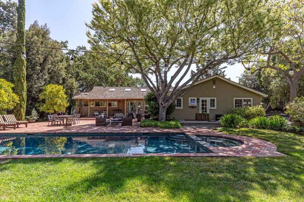 Set back 200 ft from Magdalena Ave on a quiet private lane, this beautifully-designed single-level home is a verdant retreat blending an organic color palette and high-end finishes, Zen-inspired gardens, and the best of California indoor/outdoor living and entertaining. Thoughtfully designed with vaulted ceilings, numerous operable skylights, and walls of windows, the residence offers picturesque views of lush gardens from every room. Entertain in the vaulted living and dining rooms, relax in the open skylit great room, and prepare wonderful meals in the gourmet kitchen outfitted with top-tier appliances, incredible storage, an oversized granite island, and butlers pantry. Three bedrooms sit in a private wing, including the luxurious primary suite with a spa-inspired bath and access to the yard and pool. Architectural plantings, mature trees, gardens, and idyllic sitting areas surround the home, and the backyard features a sparkling pool and spa, extensive brick patios, a fire pit patio, and seating areas shaded by mature olive and cypress trees. A detached two-car garage includes a finished upper-level office/den and has a covered breezeway connecting to the main house. Luxury living, just moments from Rancho, major commute routes, downtown amenities, and top Los Altos schools.