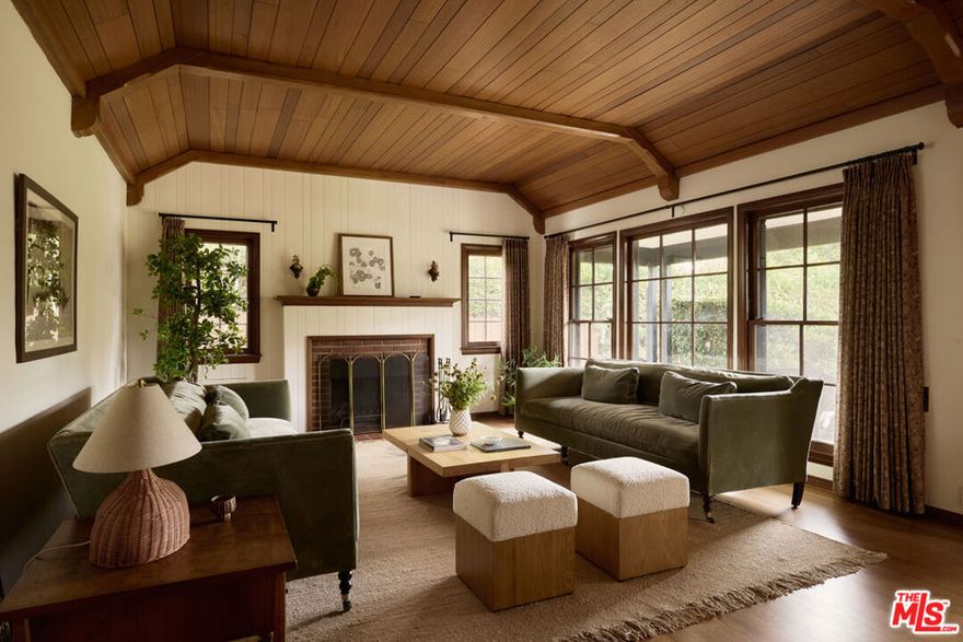 Set behind a classic picket fence and framed by lush landscaping, this 1932 English Tudor radiates timeless character. A brick walkway guides you to the entry, where the interiors reveal a spacious living room filled with natural light. Original architectural details shine here, including a striking wood-paneled ceiling, vintage windows, and a fireplace accented by period lighting. The dining room is anchored by a dramatic arched window and connects to the eat-in kitchen with breakfast bar. Upstairs, a versatile bonus room offers the perfect retreat for work, play, or relaxation. The home provides three bedrooms and three bathrooms, two of which feature private en suite layouts. Outdoors, the whimsical grounds are designed for both beauty and leisure, with a pergola-shaded patio, a stone fountain, and mature fruit trees creating a serene setting. Completing the property is a detached garage draped in bougainvillea - ideal as a studio, office, or guest space. Recent updates include a new roof, HVAC, updated electrical, new insulation, tankless water heater, upgraded sewer line, electric car charger, and more. Adding to the home's character, a hidden wine cellar lies beneath the kitchen, completing this rare 2,000+ sq ft offering in Pasadena's cultural heart.
