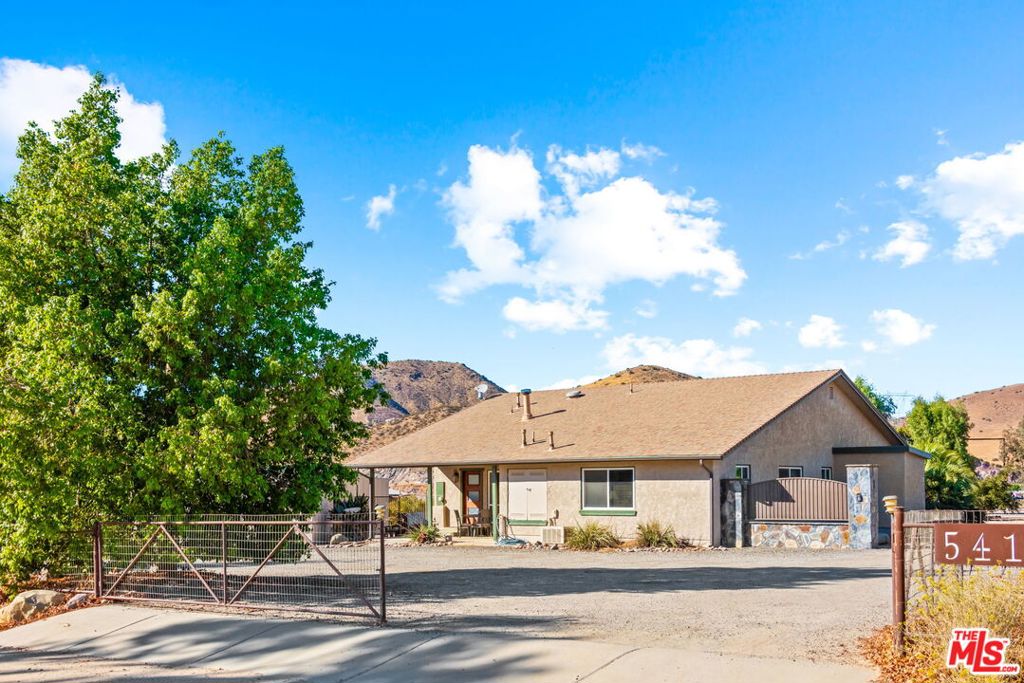 Discover the endless possibilities of this unique property, nestled on 2.5 flat, usable acres, zoned for horses and agriculture. This charming single family home boasts hardwood floors, a cozy wood-burning stove in the living room, and a kitchen with granite countertops and stainless steel appliances. Enjoy the stunning backyard views from the large covered patio, perfect for entertaining with its built-in BBQ area and palm trees swaying in the breeze. The property offers versatile outdoor features, including a custom two-level shed, a shed for pump equipment for the water well, (which is on the property and is shared with the neighbor), with extra storage, multiple RV hook-ups, and ample space for expansion. The custom-built 4-car garage with a workshop in the rear and a 2-car garage with additional carports in the front, provide abundant storage and workspace for projects (permits for the larger garage and sheds to be verified by the buyer). With breathtaking views, and vast yard space, this property is an ideal blend of rural charm and modern convenience, ready to be tailored to your vision. A must-see!