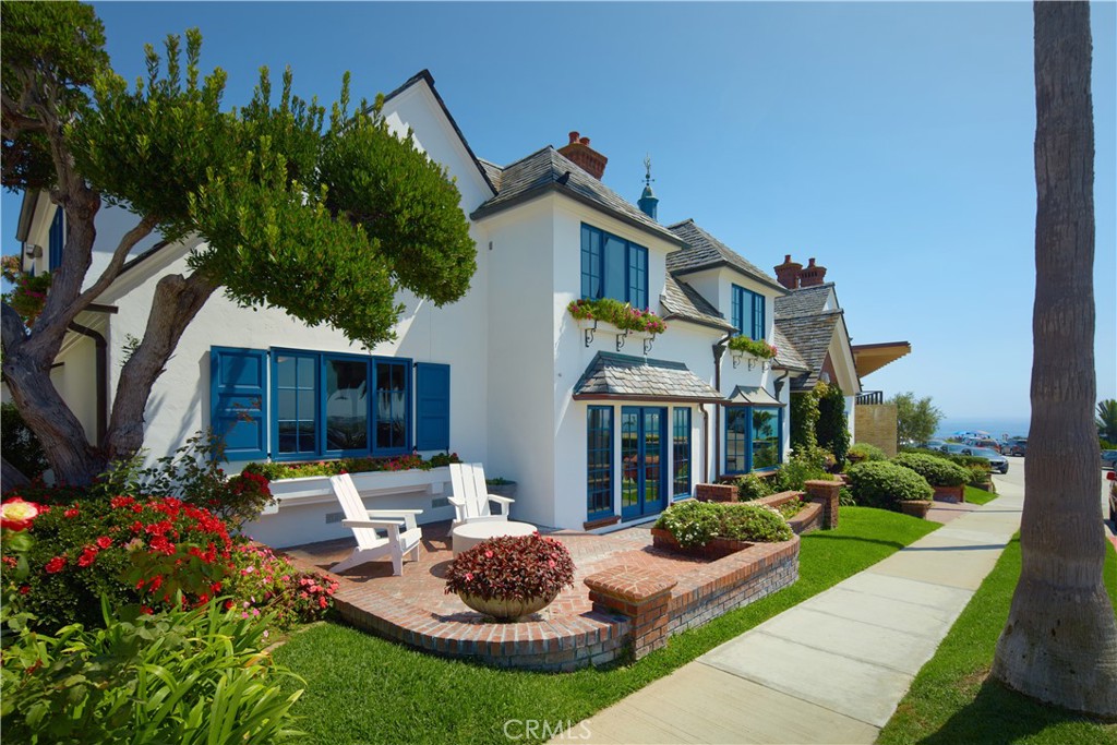 Boasting charm, a prime location, and stunning views, this coastal gem by renowned architect Brion Jeannette is available for the first time and offers an unparalleled living experience in the heart of Corona del Mar with 96' of west-facing frontage. Designed to capture uninterrupted vistas of the Pacific Ocean, Catalina Island, Peninsula, city lights, and Newport Harbor Jetty, this French Country-style cottage is situated on a unique 65' deep corner lot, spanning across two combined lots-- which cannot be duplicated today. Spanning approximately 4,770 square feet, the sun-filled interiors feature four bedrooms and three-and-a-half bathrooms. A charming living room, warmed by a wood-burning fireplace, seamlessly flows into a formal dining area. Adjacent, is a secondary living room where a garden window bathes the brick-surround fireplace in natural light. This inviting space opens to a delightful kitchen, complete with a sunny breakfast nook, an island, wood cabinetry, and new quartz countertops. The main level is rounded out by a powder room and an en suite bedroom offering a jacuzzi tub. Throughout the home, you'll discover character in every corner—antique leaded glass, beamed ceilings, wood flooring, new carpeting, and crown molding. Wood-framed doors open to a rare, beautifully landscaped backyard with multiple patios and a barbecue area, offering effortless grand-scale entertaining in a serene setting where ocean breezes and tranquility converge. Upstairs, three bedrooms await, including the sumptuous primary suite. This retreat offers an ocean and city lights view balcony, cozy fireplace, oversized marble walk-in shower, jacuzzi tub, marble vanity area with dual sinks, and a bonus room that could serve as an exercise space. Down the hallway, a private office with built-in shelving and another bonus room with an en suite full bath provide versatile spaces for work or leisure. Atop the home, the rooftop deck offers breathtaking views of the world-famous surfing spot, "The Wedge," where waves reach captivating heights. An oversized two-car garage with laundry completes the home. With panoramic views spanning the ocean horizon, Catalina Island, and Newport Harbor, this residence is perfectly positioned to appreciate Newport Beach and Corona del Mar's most iconic sights. All this, while being just moments from renowned beaches, Lido Marina Village, and John Wayne Airport.