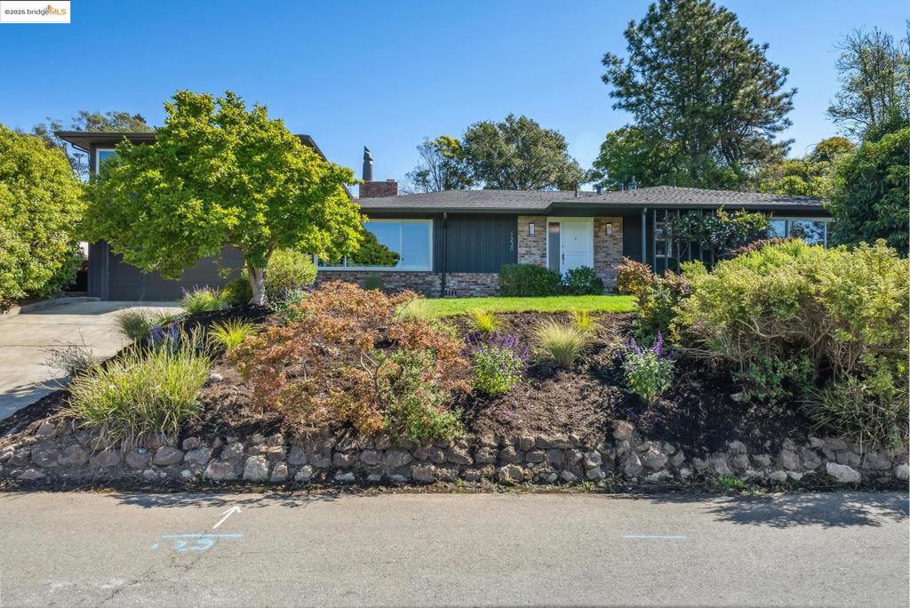This four-bedroom, two-bath home in El Cerrito is a quintessential expression of mid-century modern design—thoughtful in layout, vibrant in character, and oriented toward effortless indoor-outdoor living. With mostly one-level functionality, it combines classic style with everyday comfort. The private patio and inviting pool set the scene for year-round enjoyment and relaxed entertaining. The living room makes a striking first impression with a large picture window that wraps the corner of the room, a brick fireplace that anchors the space, random plank hardwood floors, and easy access to the family room and the upper lounge. These timeless details embody the home’s mid-century spirit. In the adjacent formal dining room, a sliding door—spanning the wall—leads directly to the backyard and pool. The kitchen/family room also connects to the patio, creating a natural hub for gathering. Baths, including the primary ensuite, have been updated and two-car garage has interior access. Upstairs, a lounge with vaulted ceiling (technically the 4th bedroom) and adjacent sunroom are wrapped in walls of windows, offering wide outlooks and glimpses of the Bay. Rough-hewn wood accents and floating shelves add personality. This peaceful upper-level retreat is the home’s unexpected gem.