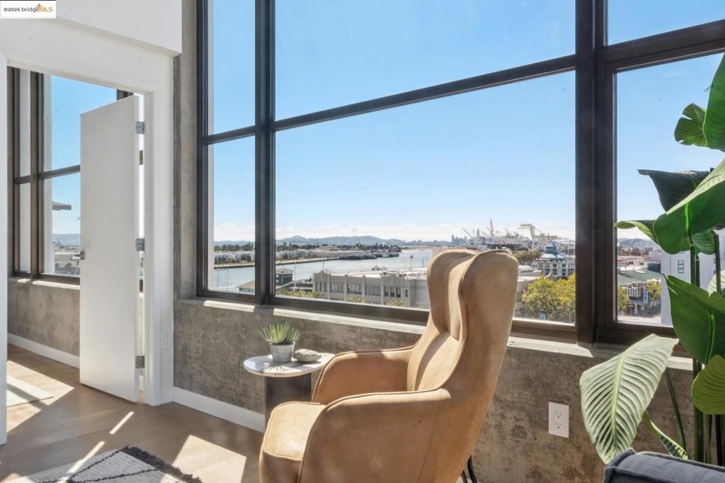 Perched atop The Bond, an architecturally striking steel-and-concrete building completed in 2009, this southwest corner penthouse offers sweeping views and sophisticated urban living in Oakland’s vibrant Waterfront Warehouse District. Residence 816 features soaring 14-foot ceilings and dramatic wraparound windows that flood the space with natural light while framing iconic views of the Jack London Marina and San Francisco & Oakland skylines. This rare 2-bedroom, 2-bath + open den/office layout is among the most sought-after floorplans in the building. The spacious living area enjoys both northern and southwestern exposures and flows seamlessly into a sleek kitchen outfitted with modern cabinetry, a generous breakfast bar, and high-end finishes. The primary suite offers a tranquil retreat with a spa-like bath that includes a soaking tub, separate stall shower, and a large walk-in closet. A second bedroom, adjacent to the flexible den space and second full bath, offers guests or family members ample space and comfort. Located just one block from Jack London Square’s waterfront, The Bond is surrounded by destination restaurants, cafés, breweries along the Oakland Ale Trail, live music venues, and a movie theater. Commuting is a breeze with nearby access to BART, Amtrak & ferry. Views: Downtown
