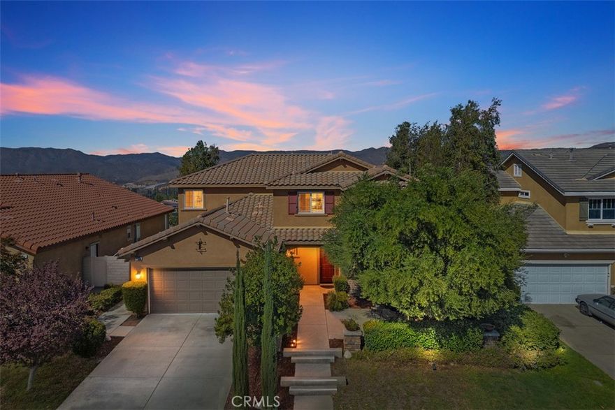 This stunning former model home in Amberhill Ranch offers panoramic mountain views from its elevated 5,663 sq ft lot and features five spacious bedrooms, (including a main-floor suite), plus a versatile upstairs loft. The formal dining room has a butler's pantry and flows seamlessly into a gourmet kitchen equipped with rich wood cabinetry, wood floors, granite countertops, stainless steel appliances, a large island, and abundant storage. The great-room style family room boasts surround sound, a cozy fireplace, and breathtaking views.  The nearby main floor bedroom with en-suite bathroom is great for guests.  Upstairs, the luxurious upstairs primary suite includes crown molding, built-in speakers, and a spa-like bathroom with travertine floors, dual sinks, a soaking tub, separate shower, and oversized walk-in closet. Additional highlights upstairs include the large bonus room/loft, three additional bedrooms, dual-sink bathroom, an upstairs laundry room, whole-house fan, and dual-zoned A/C. The flat, usable backyard offers privacy, breezes, and space for a pool or play area. 3 car tandum garage offers convenient space options. Located within walking distance to a new elementary school and resort-style HOA amenities including a pool, splash zone, clubhouse, and parks, this home is just minutes from the I-15 freeway, Lake Elsinore Outlets, and the lake, plus offers easy access to Corona, 25 min to Temecula and 50 min to Orange County.  This property is the perfect place to call home.